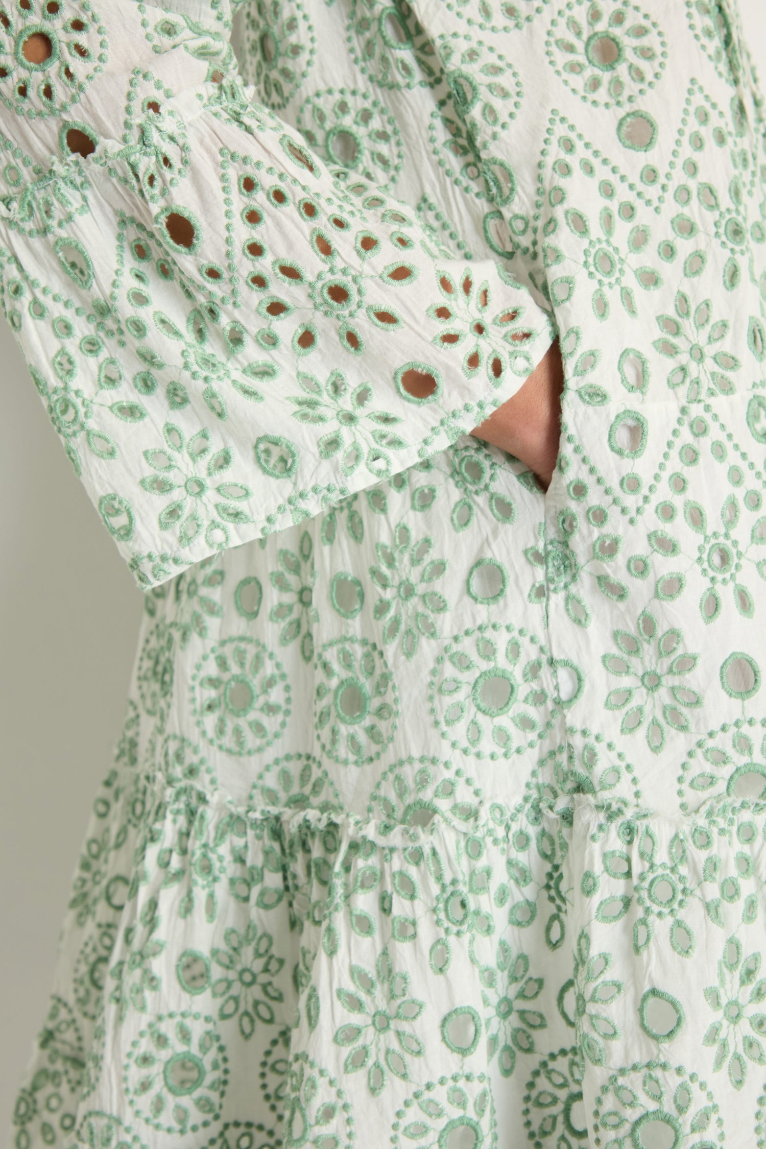 Close-up of a person wearing the Embroidered Circle Flared Sleeve Tunic in white with green circular patterns, featuring a hand placed in the side pocket.