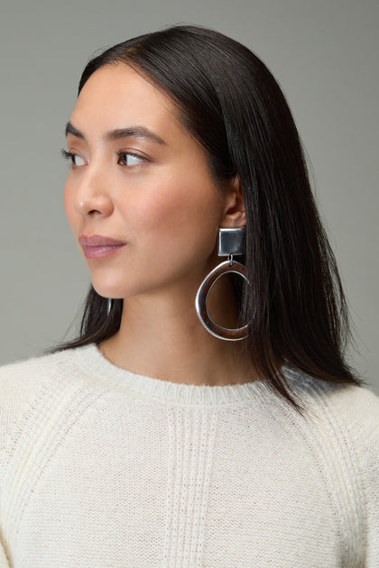 Woman with straight dark hair wears a cream knit sweater and Silver Squares Clip-On Earrings, looking to her left against a neutral background.