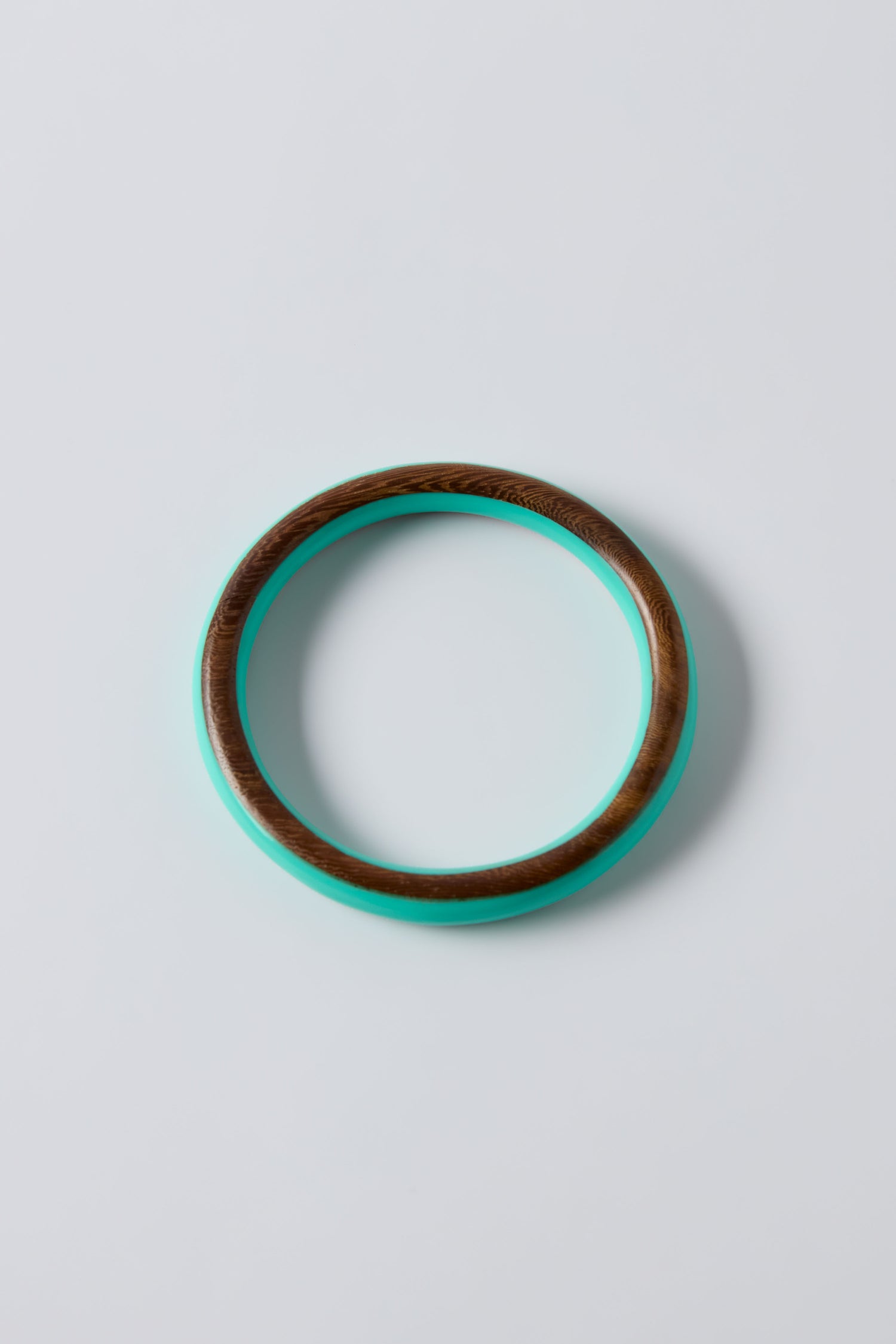 The Cosmos Turquoise Wooden Bangle features a vibrant turquoise resin interior and a wooden exterior, beautifully showcased on a plain white background—perfect for adding standout style to summer jewelry collections.
