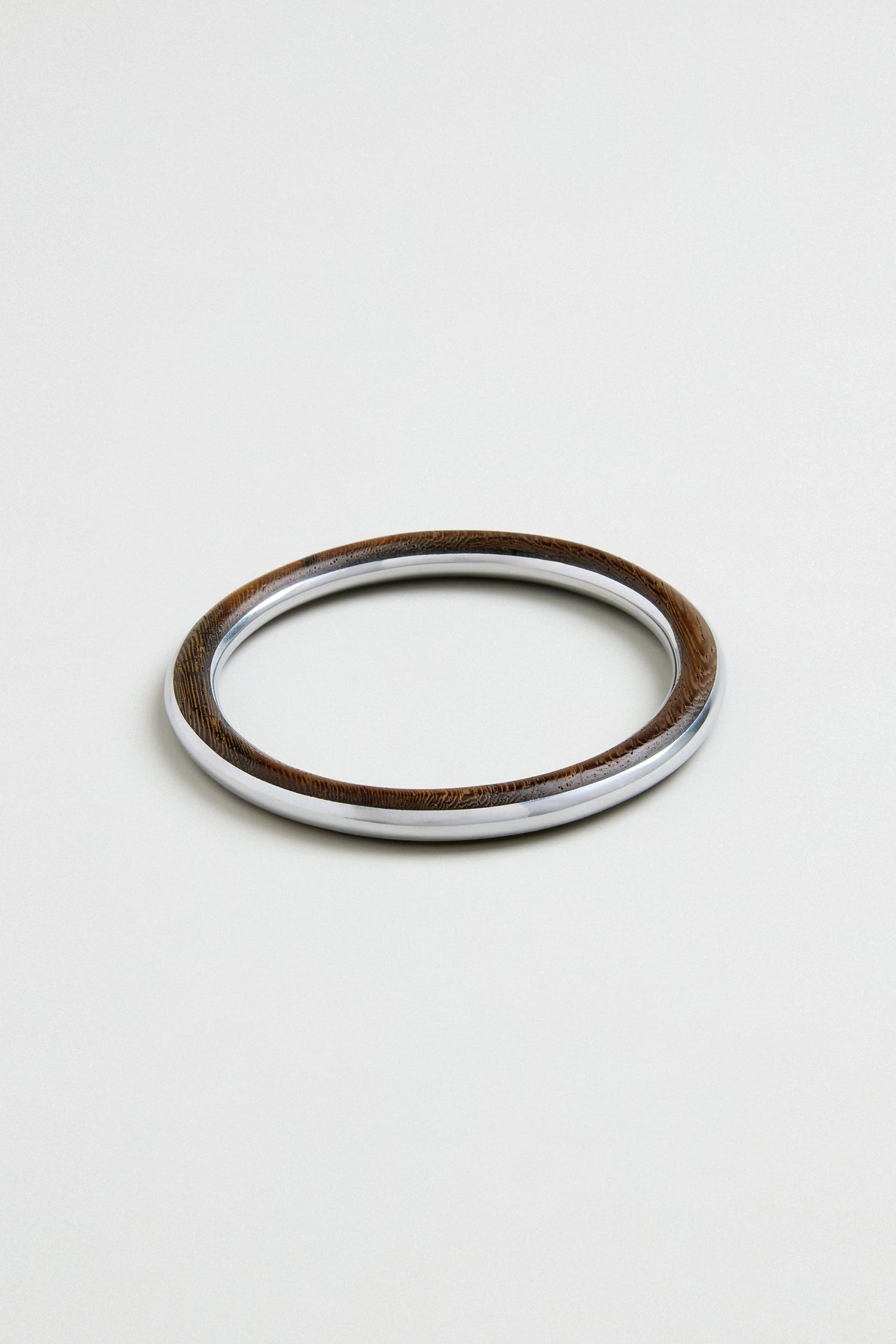 The Wooden Silver Fusion Bangle, featuring a wood-textured finish and a smooth metallic inner edge, is showcased against a plain light background.