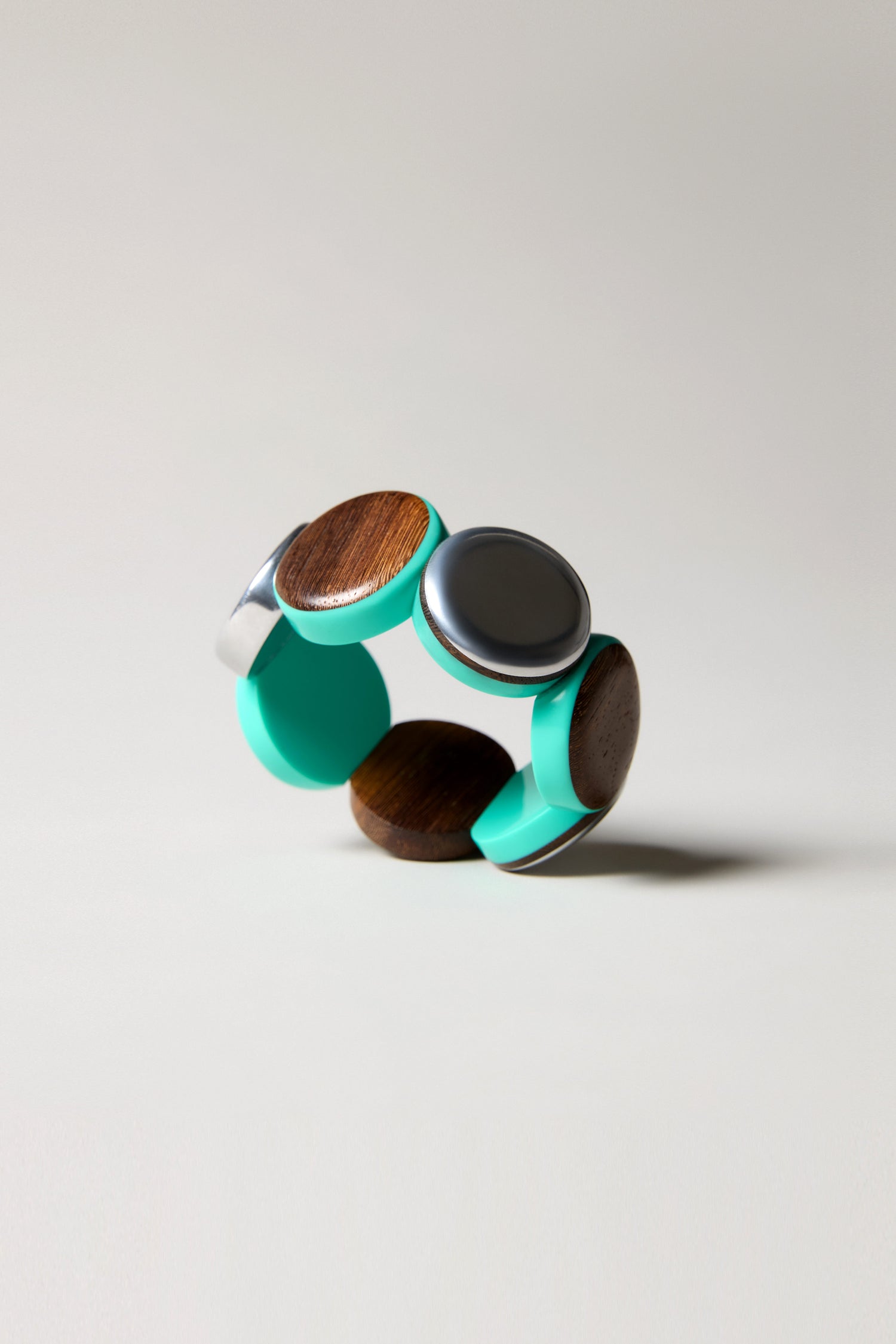 The Wooden Spheres Bracelet showcases turquoise bands, round wooden inlays, and a metallic accent, all set against a light background.