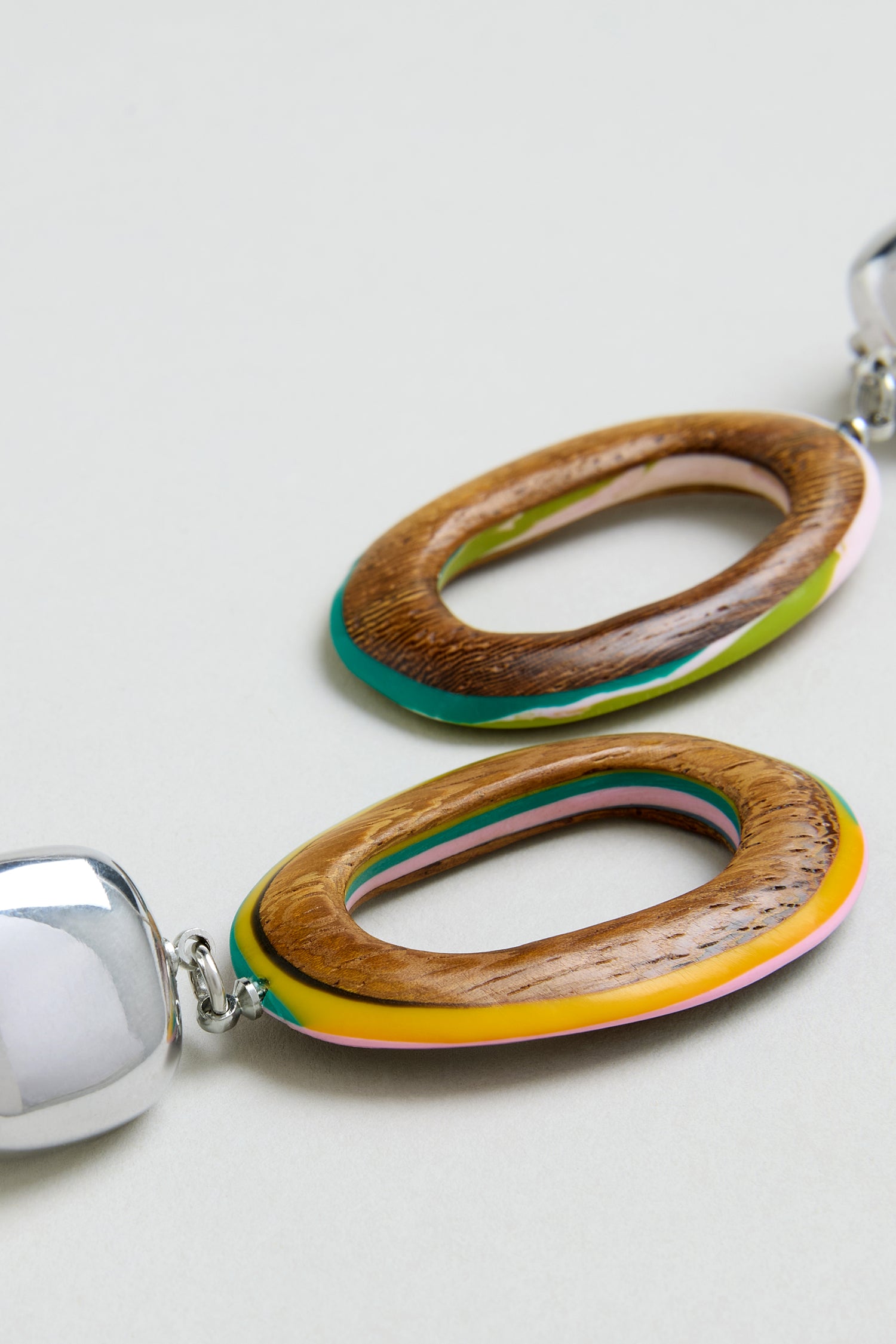 Close-up of the Rainbow Edge Wooden Clip-On Earrings, featuring bold oval wooden links with colorful accents and shiny silver connectors—perfect for lovers of statement jewellery and handmade pieces from Spain.