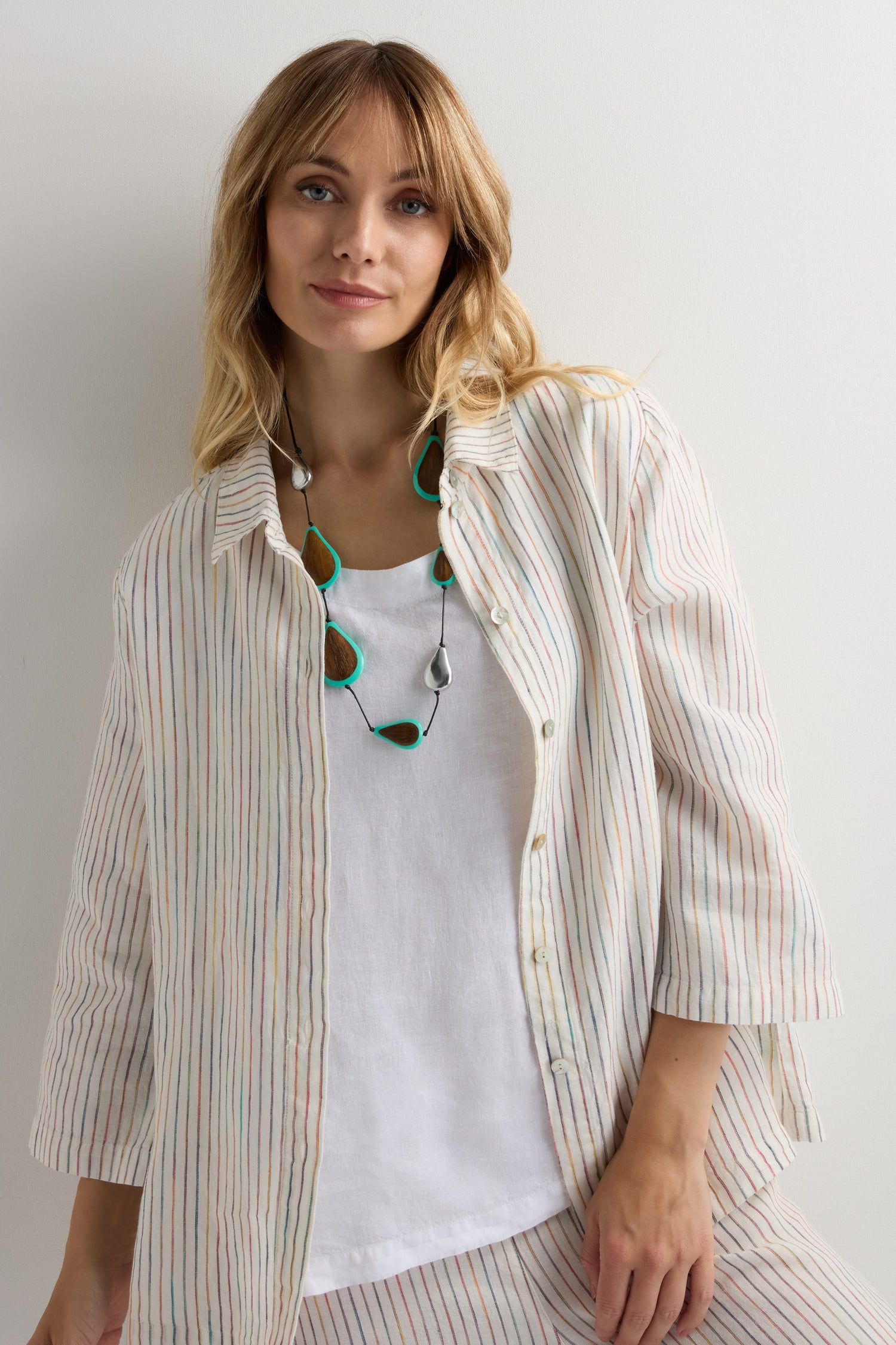 Woman with long blonde hair wearing a loose, striped button-up shirt over a white top and accessorized with a Turquoise Teardrop Necklace, standing against a plain white background.