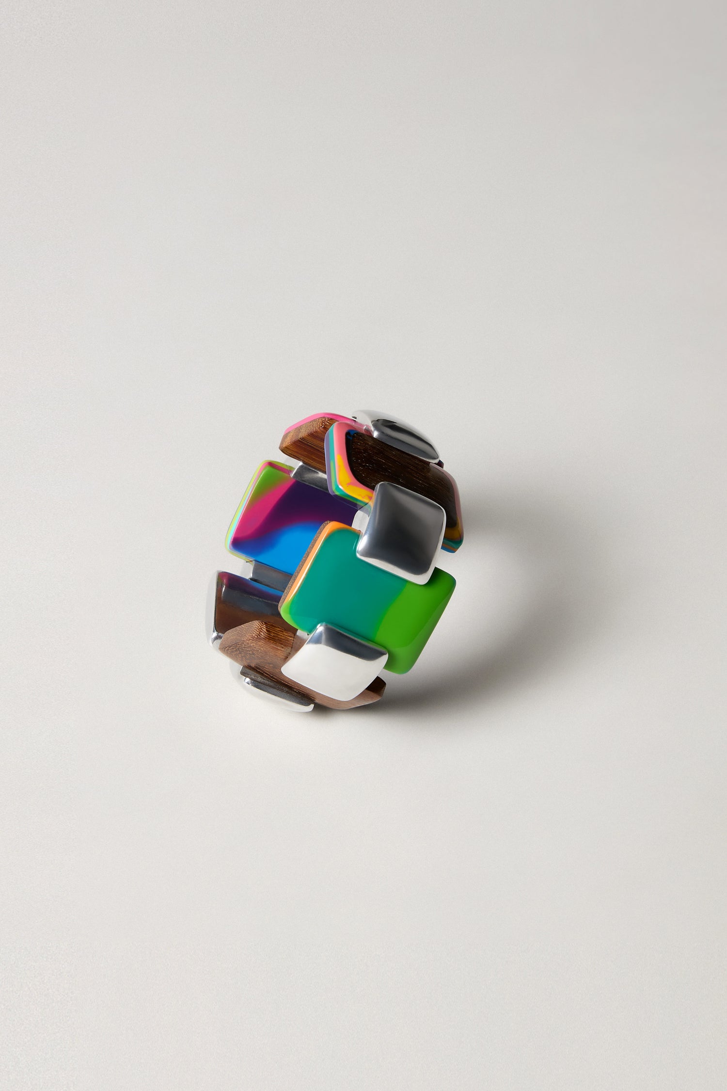 The Colourburst Squares Links Bracelet is a chunky, handcrafted accessory with large glossy square and rectangular links in green, brown, white, and marbled resin shades, inspired by Barcelona style. Displayed on a plain background.