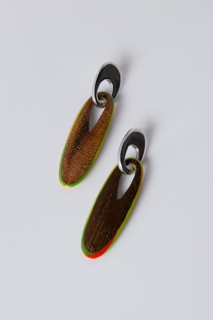 The Rainbow Wooden Oval Links Earrings feature sculptural drop design with silver tops and elongated wooden pendants accented in green and red, displayed on a plain white background.