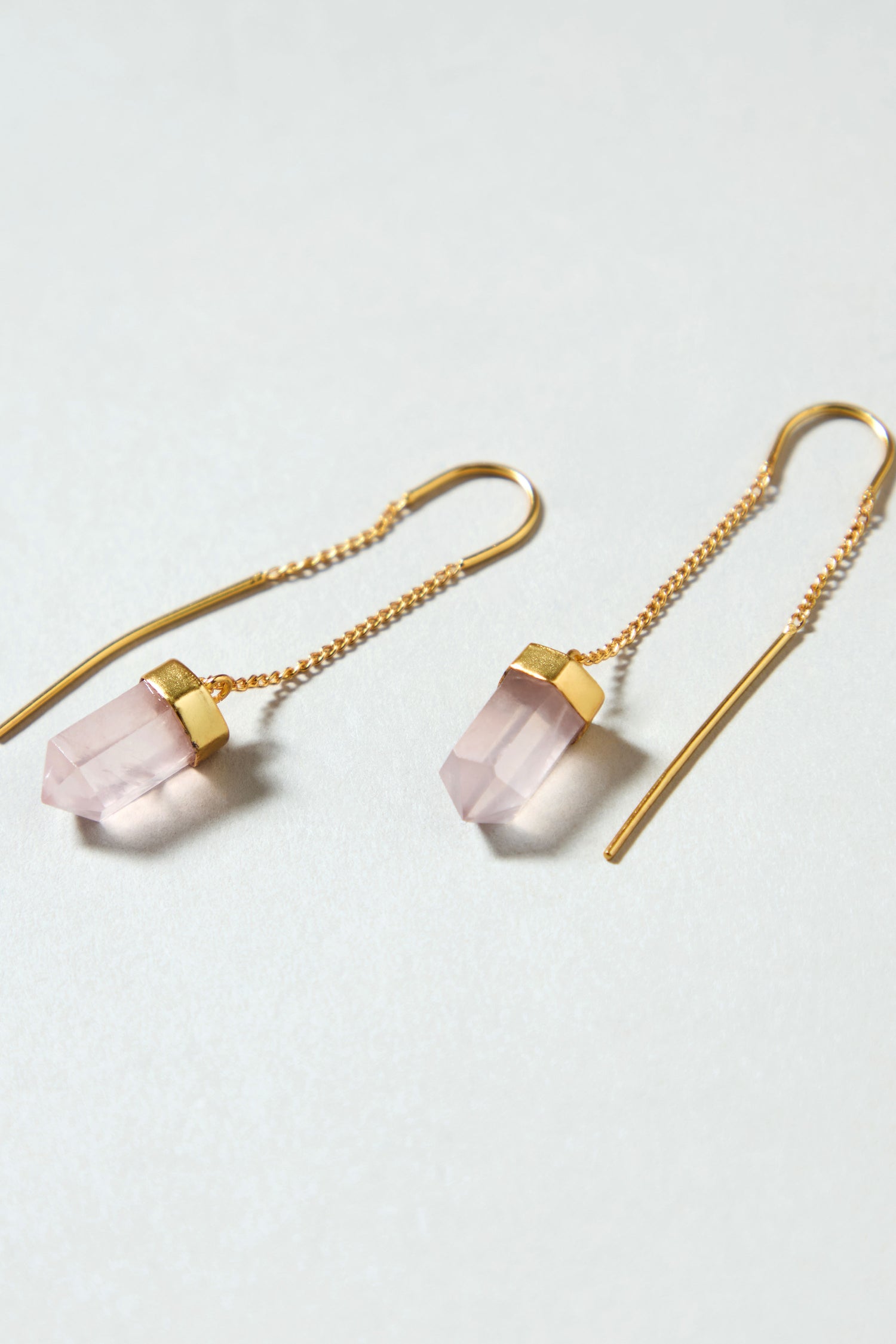 The Rose Quartz Crystal Drop Earrings feature gold plated threaders with light pink, faceted rose quartz pendants and a minimalist design—perfect for fans of handcrafted crystal earrings.