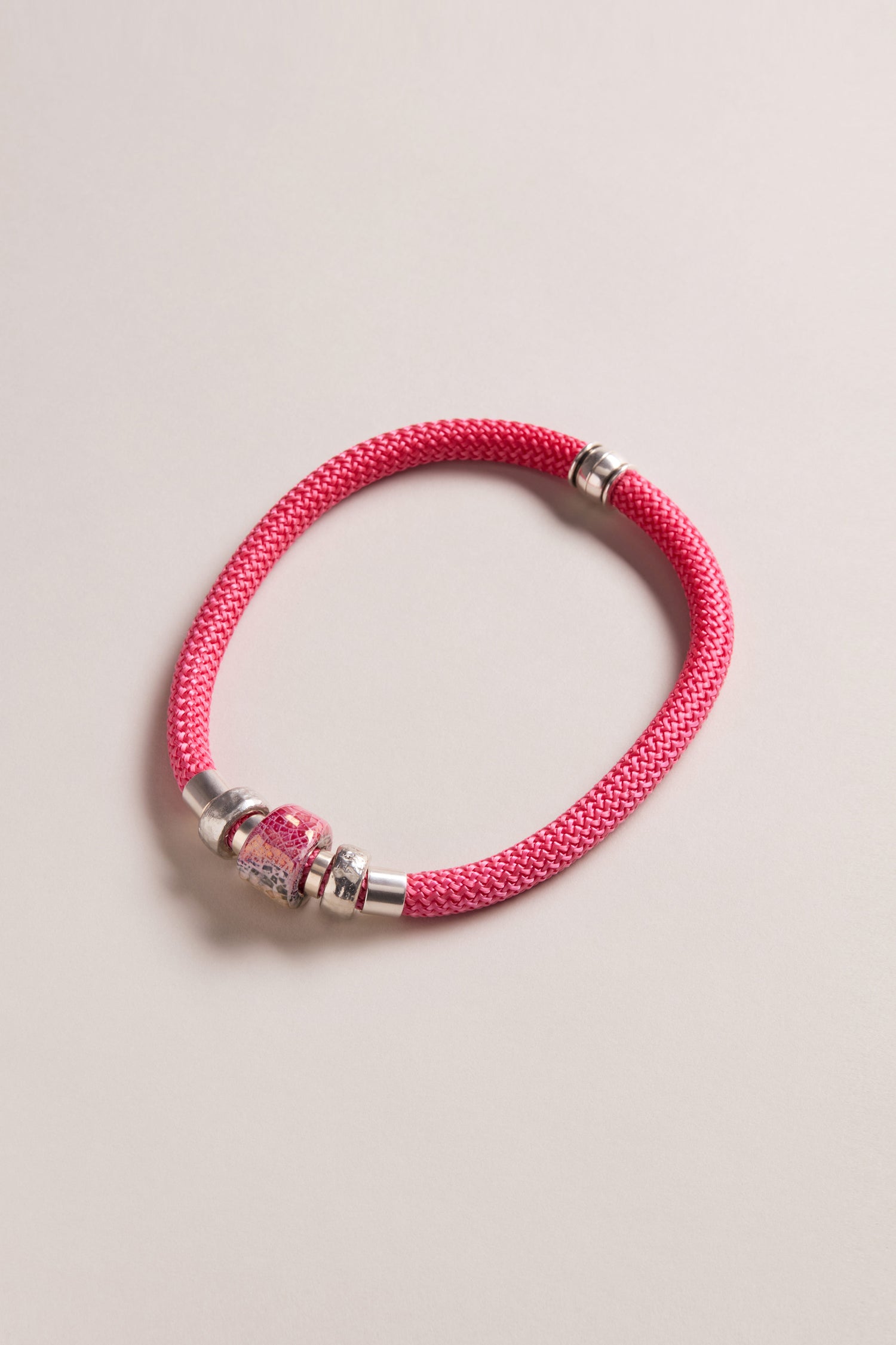 A Single Mosaic Cube Necklace with pink and silver beads, echoing vibrant magenta hues, is showcased against a light neutral background.