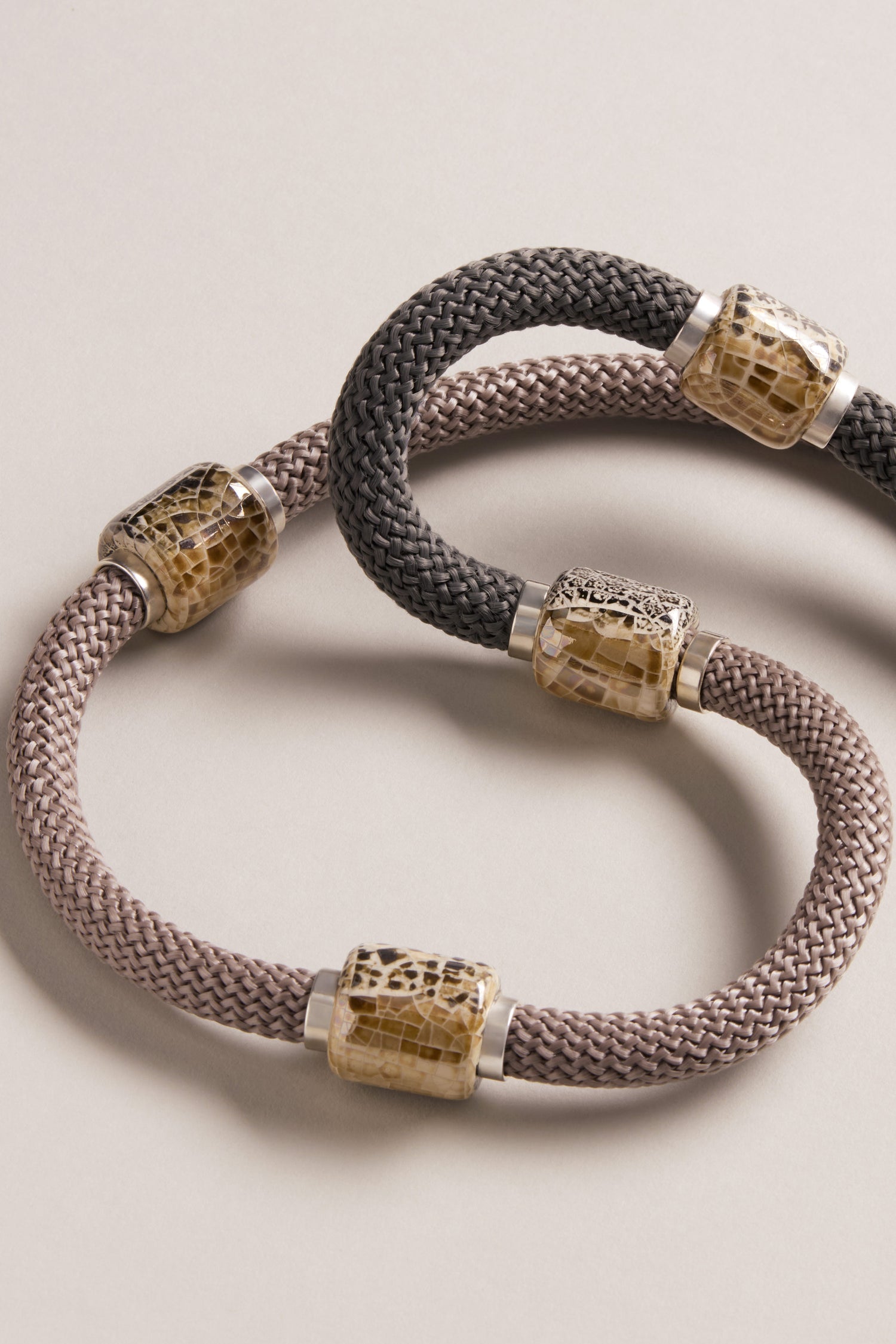 The Long Mosaic Bead Necklace features gold and silver cylindrical metal accents inspired by Mediterranean jewelry, showcased on a neutral background.