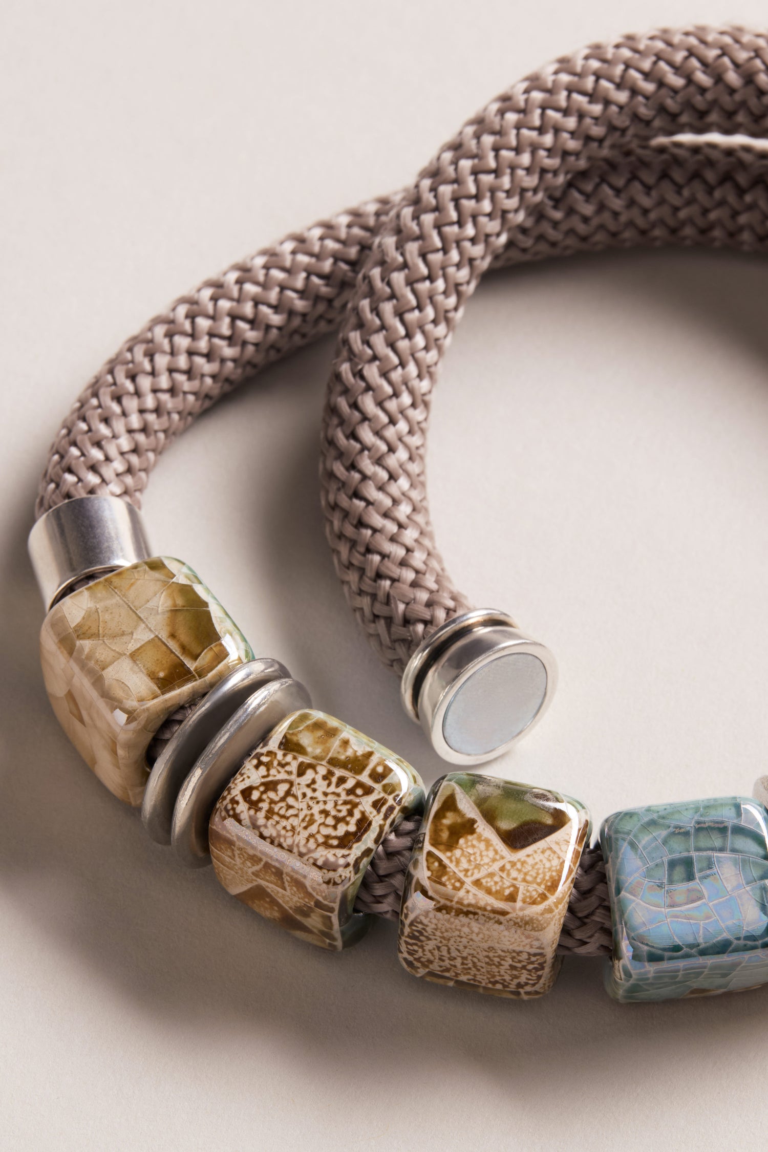 A close-up of the Short Marble Cube Necklace, featuring square, patterned marble beads in earthy tones and silver accents—a unique accessory that perfectly complements taupe and teal jewelry.