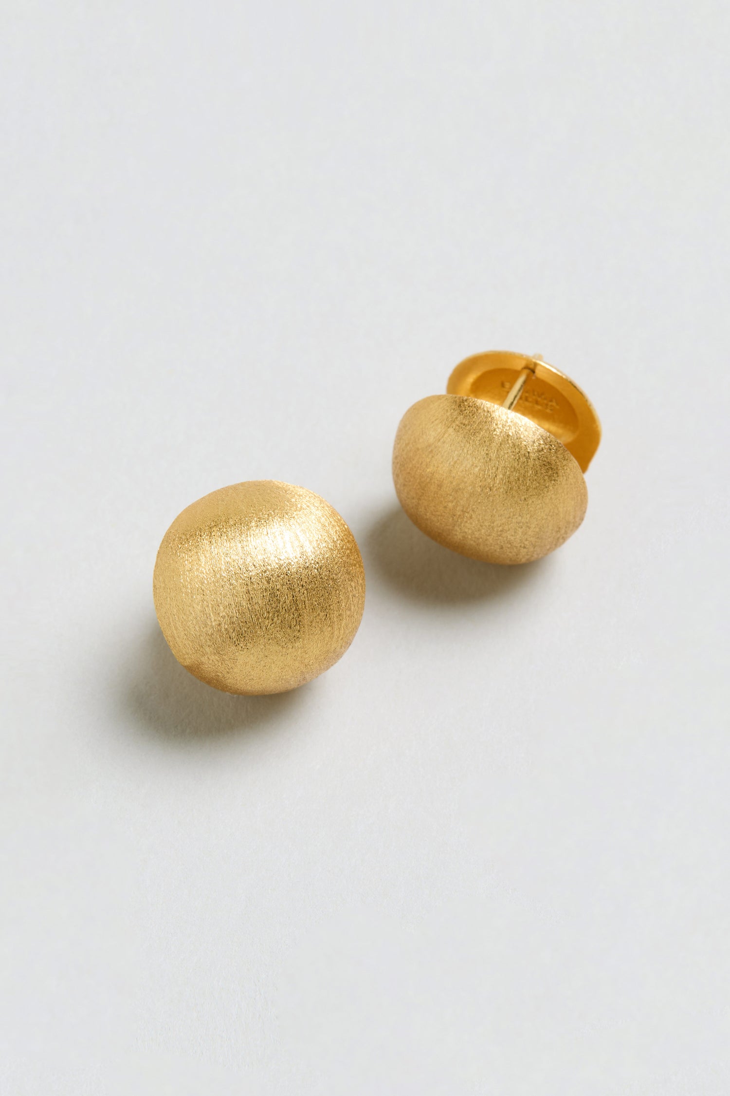 A pair of Brushed Sphere Earrings, featuring round, textured gold plating, are shown on a plain light background.