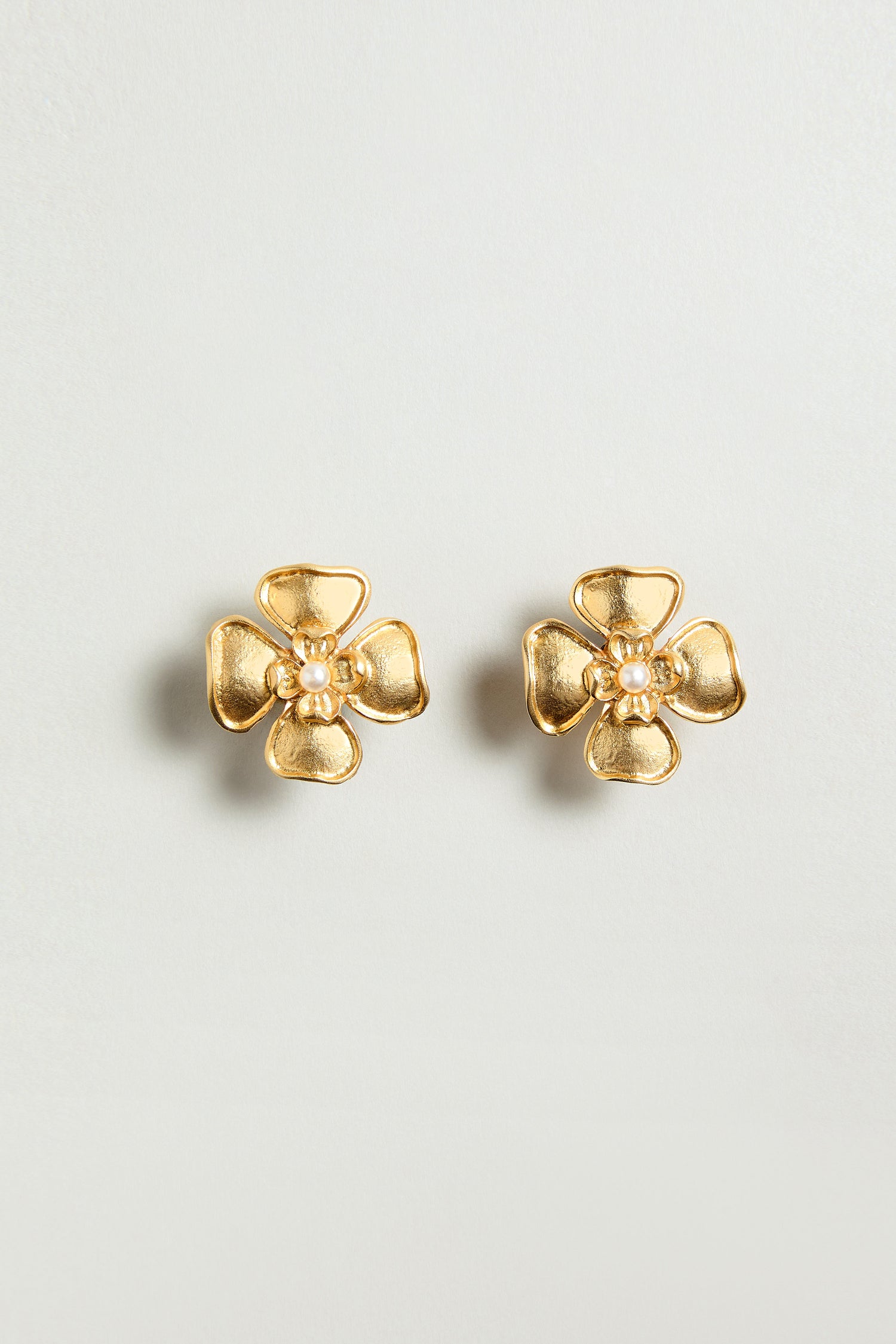 The Gold Plated Flower Pearl Earrings feature a floral design with a delicate pearl center, shown against a plain light background.
