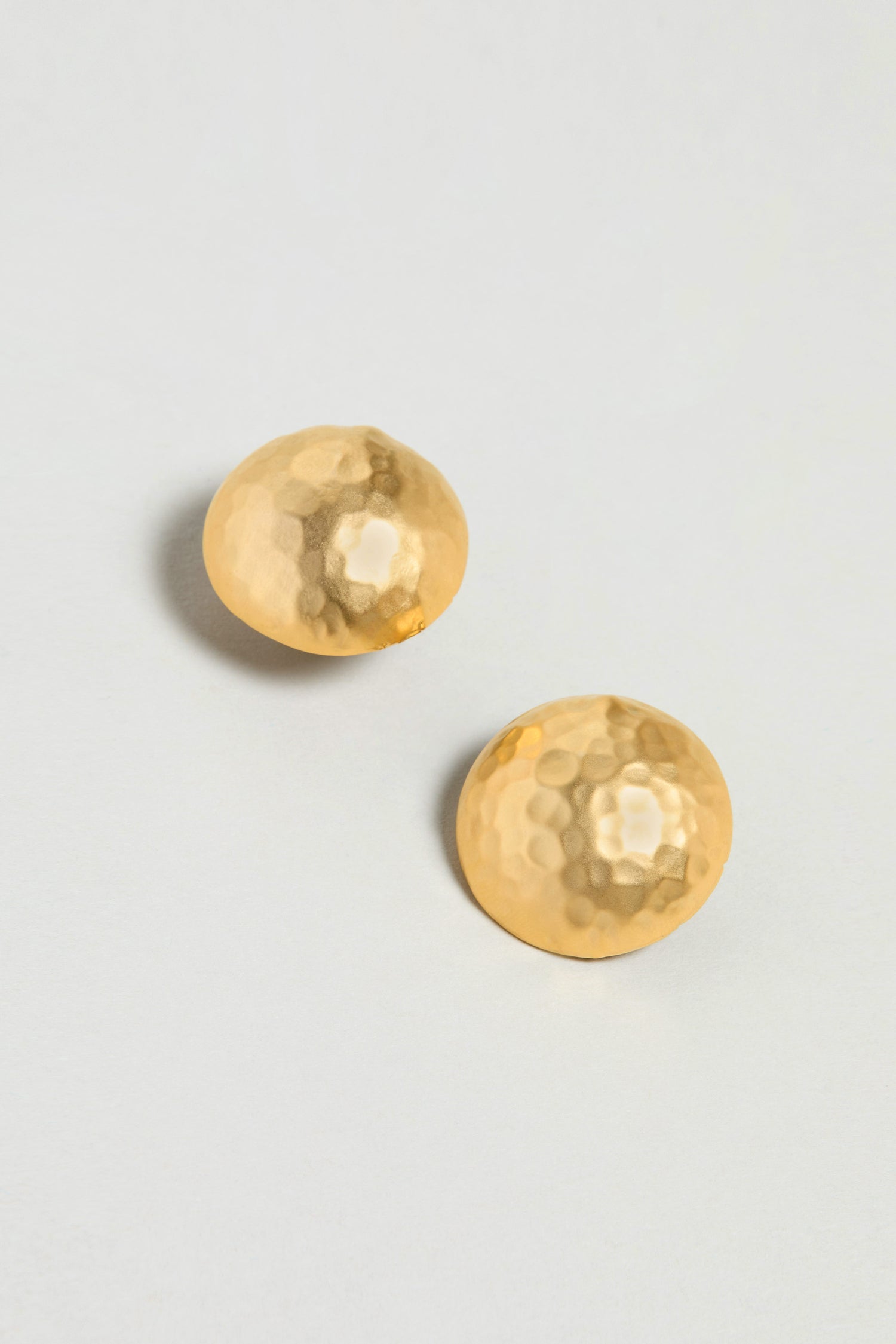 Gold Plated Hammered Sphere Earrings, featuring a round hammered design, are displayed on a plain, light-colored background.