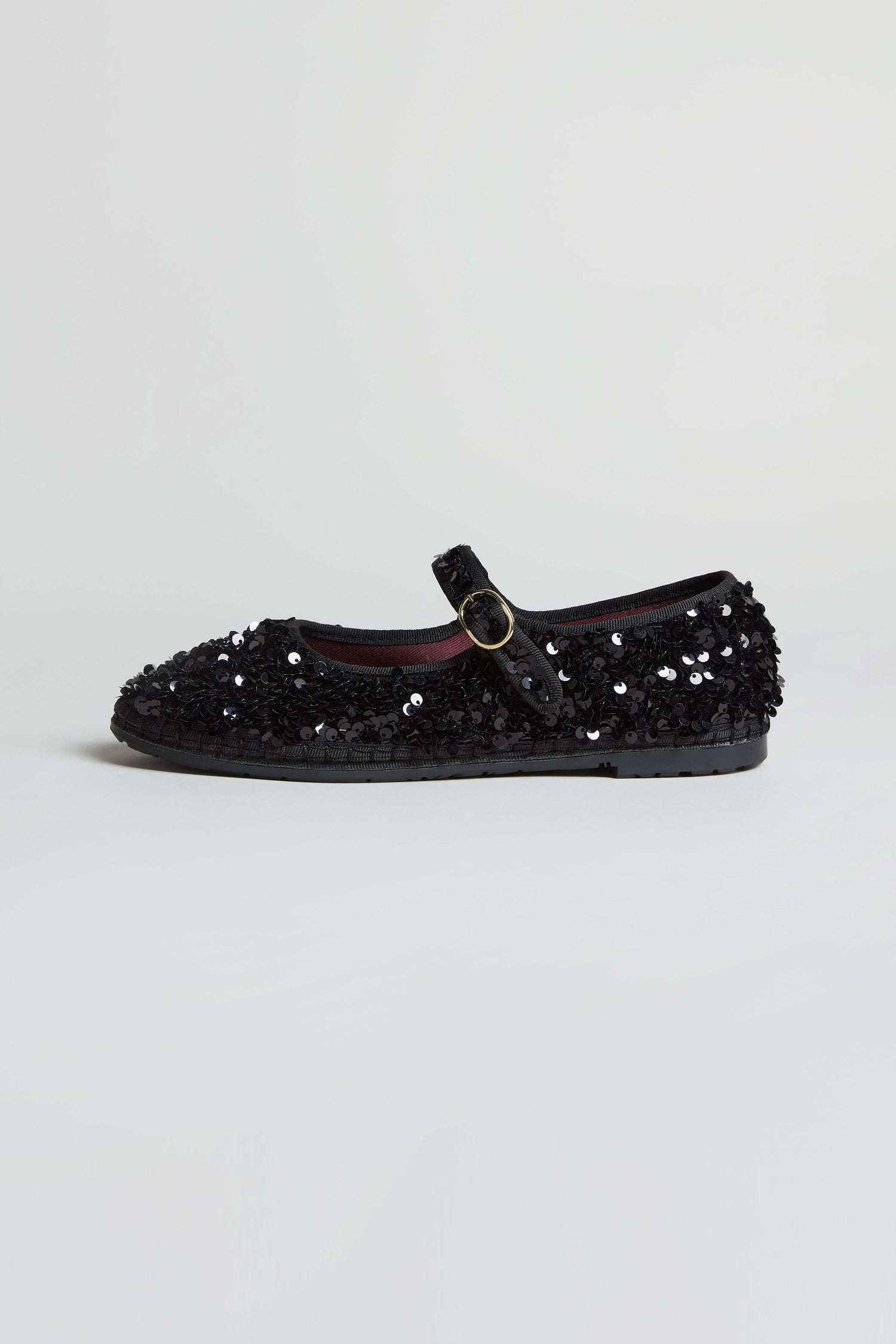The Sequin Mary Jane Velvet Shoes, handmade in Spain, feature sparkling black sequins, a single buckle strap, and a chic silhouette—displayed on a plain light background.