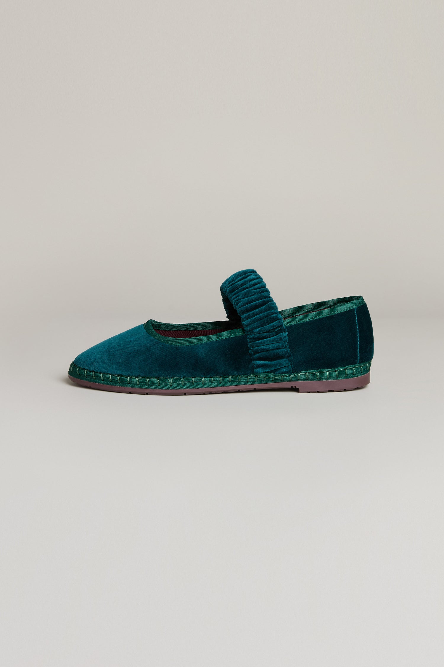 Mafalda Teal Velvet Shoes, handmade in Spain, showcase a textured strap, visible sole stitching, and a brown recycled rubber outsole. Photographed on a neutral background.