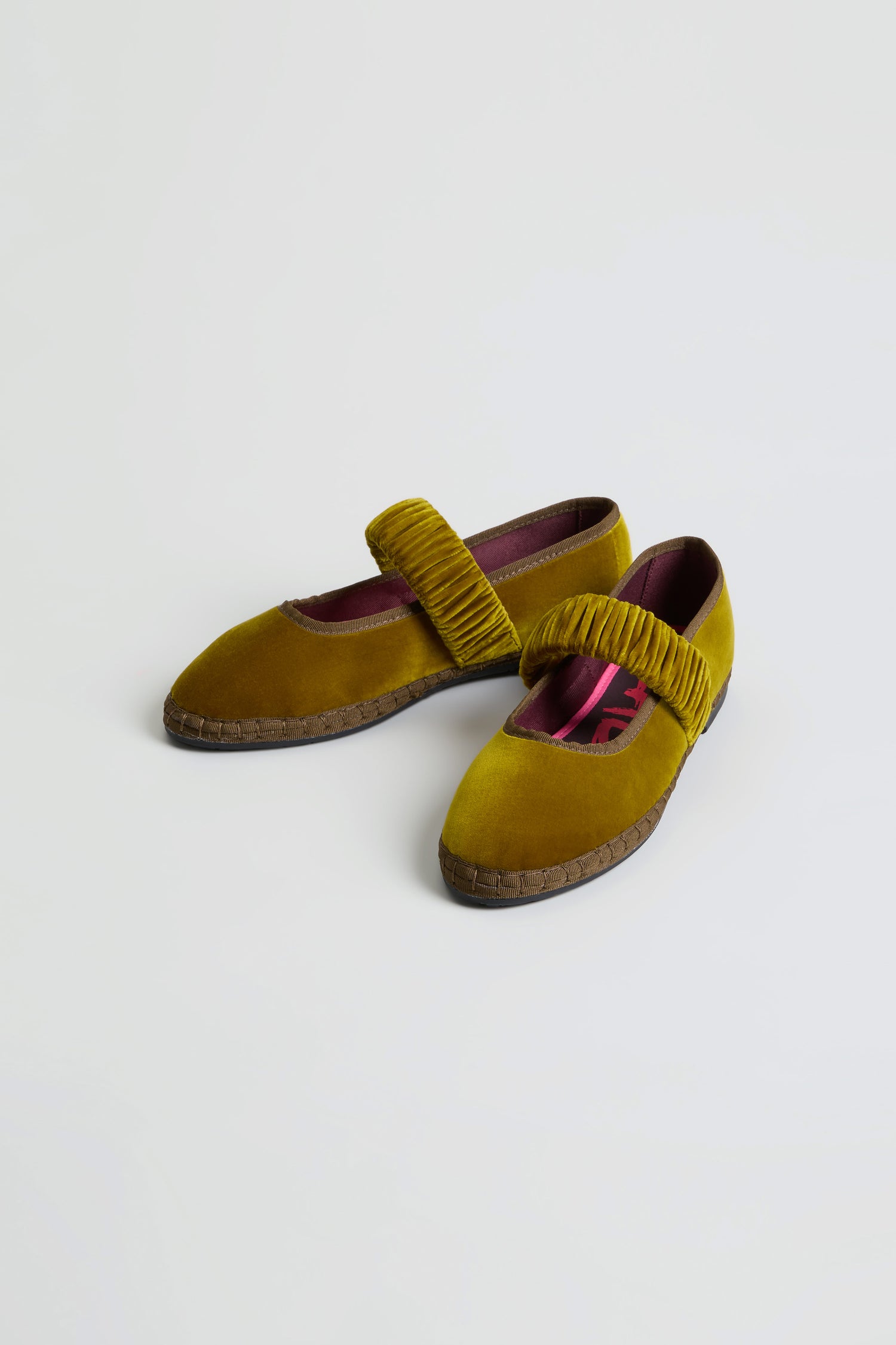 A pair of Mafalda Ochre Velvet Shoes, featuring a ruched strap and brown textured recycled rubber sole, handmade in Spain, displayed on a white background.