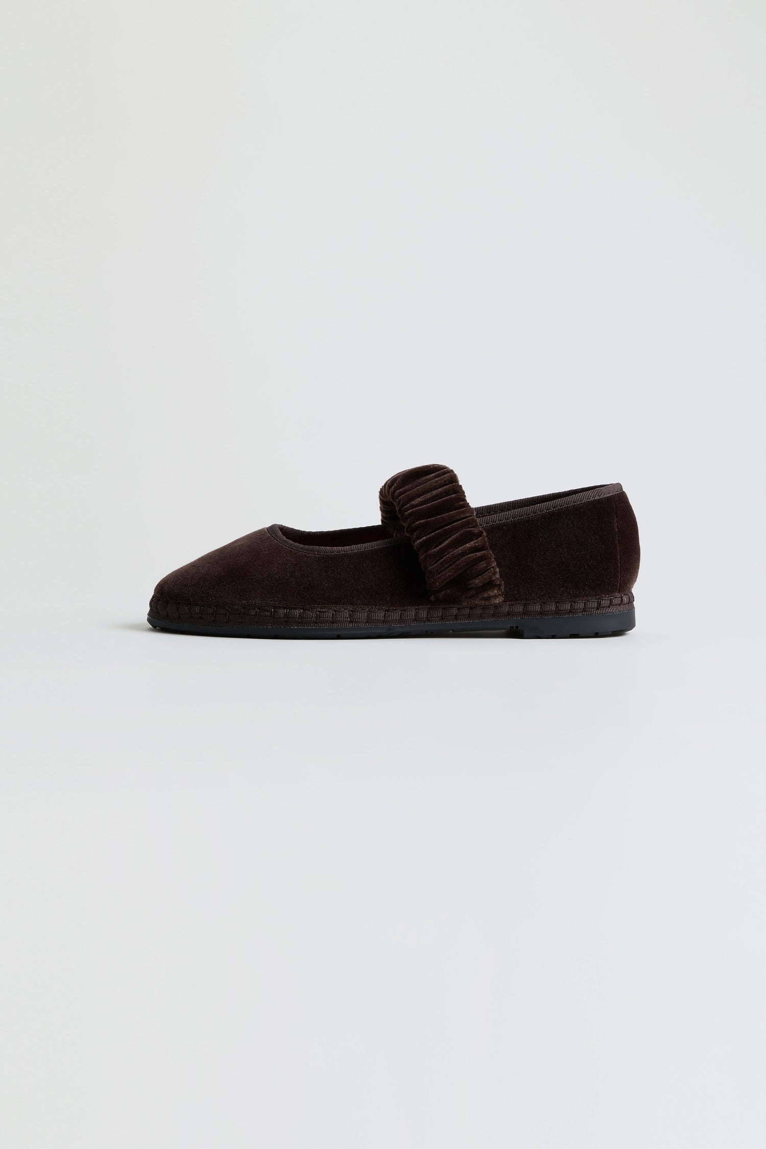 A single Mafalda Truffle Velvet Shoe, handcrafted in Spain with dark brown velvet and featuring a textured strap across the top, displayed on a plain light background.