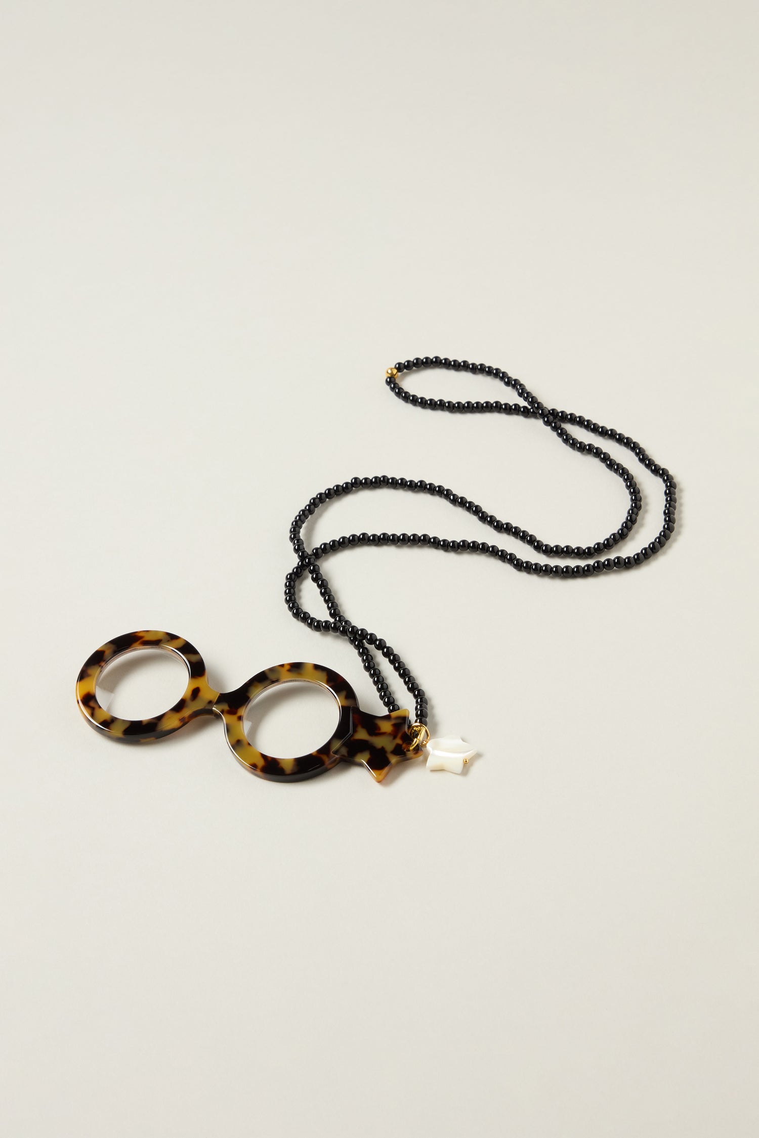 Star Pendant Glasses: Handcrafted round tortoiseshell-patterned eyewear attached to a long black beaded necklace, showcased on a simple light background.