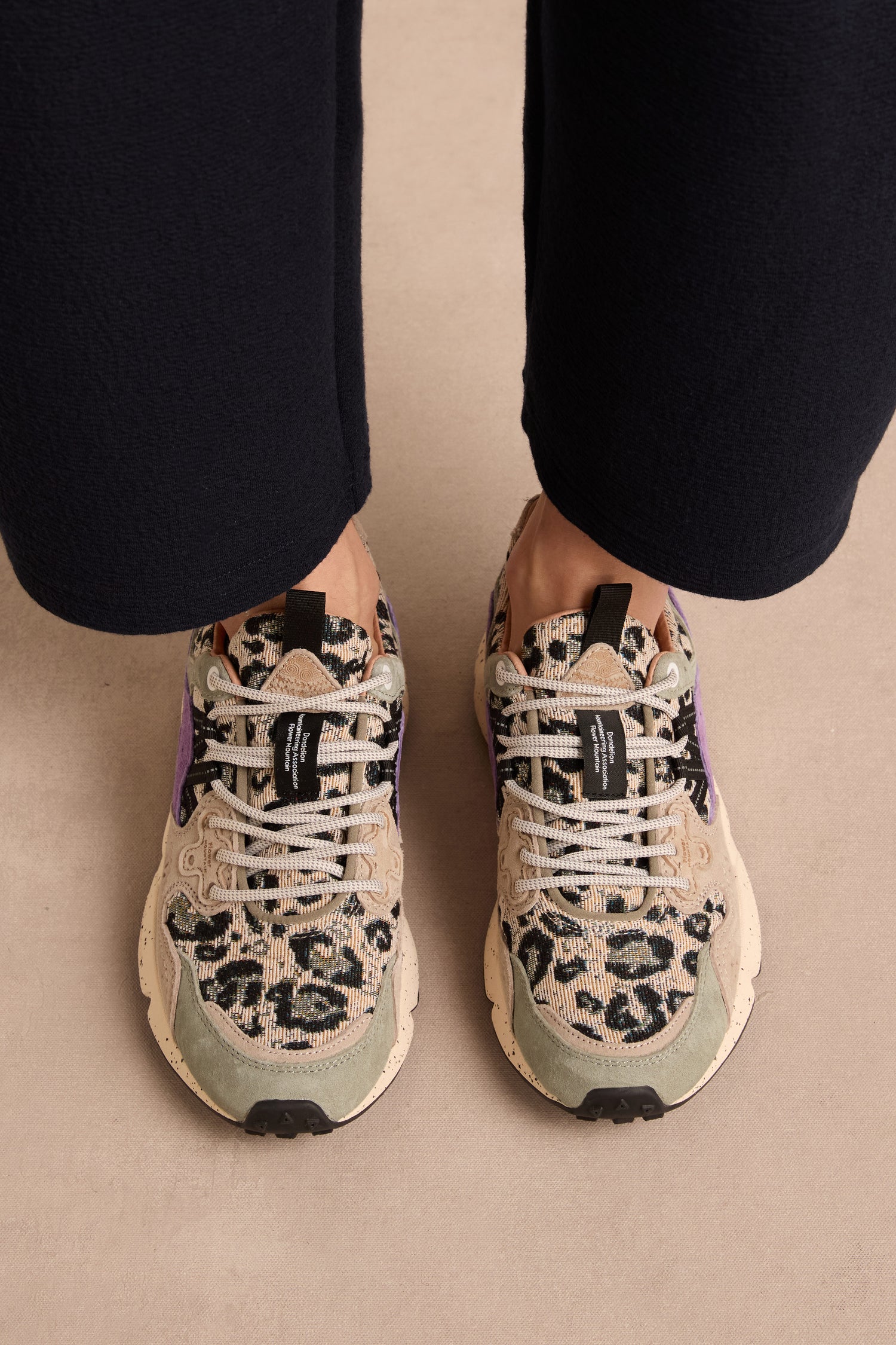 Person wearing beige pants and Yamano 3 Leopard Print Trainers with white laces and a stylish chunky sole, standing on a light-colored floor.