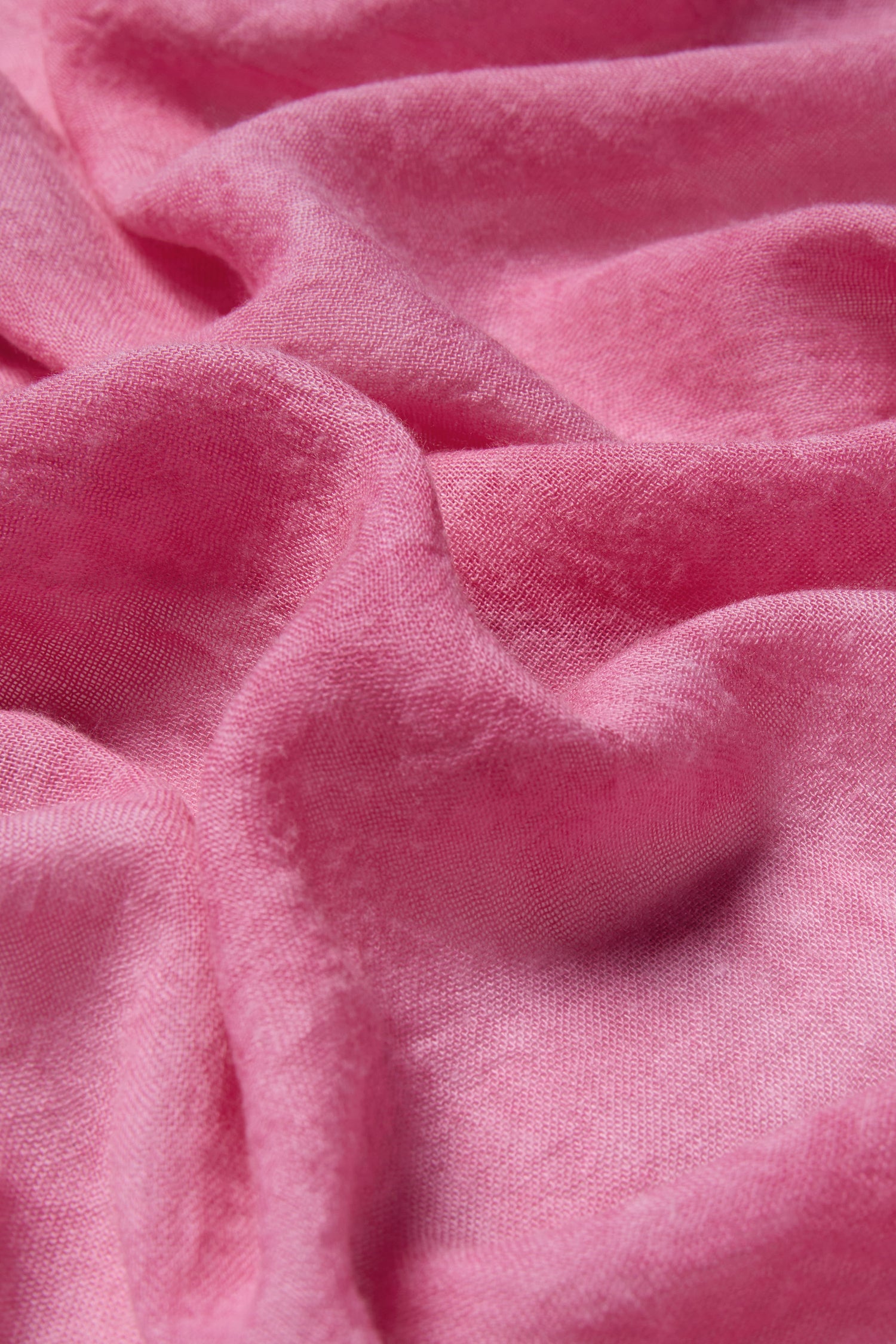 Close-up of pink, textured material with visible folds and a soft, slightly shiny surface—ideal for versatile styling or wrapping up in the cozy Soft Fringe Scarf.