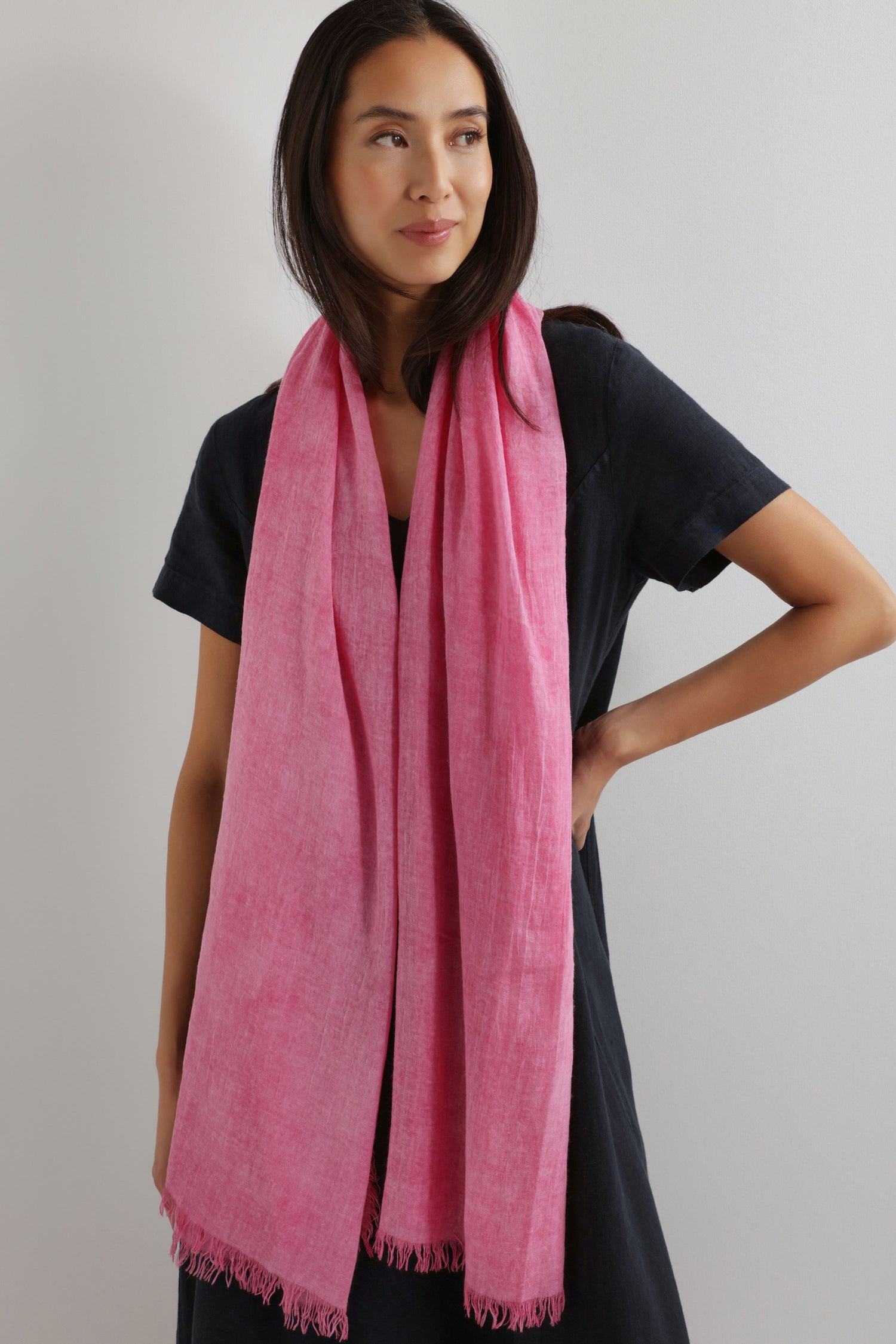 A woman in a black dress wears the Soft Fringe Scarf, standing against a plain light background to showcase its versatile styling.