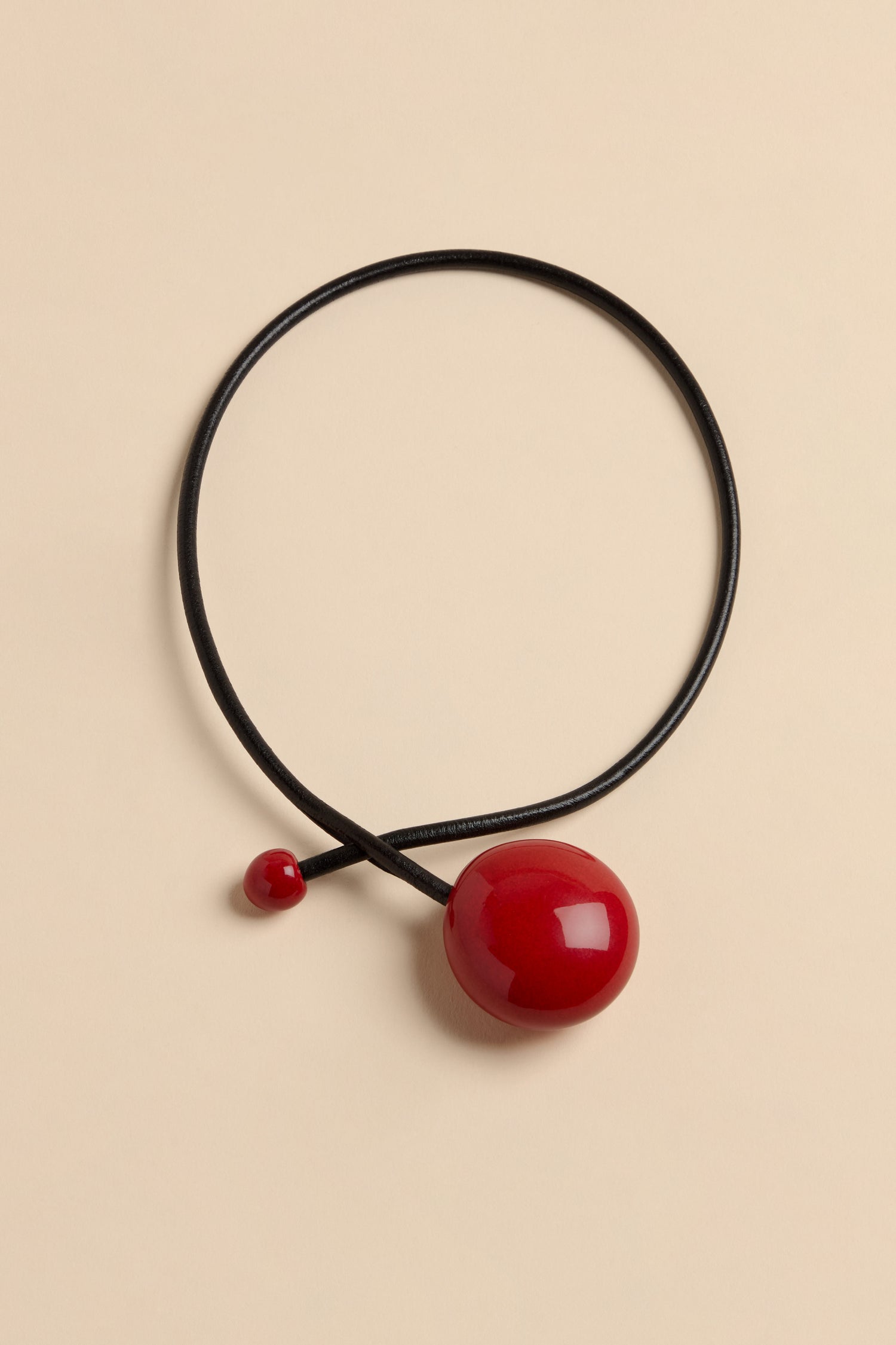 Handmade Deep Red Ceramic Bead Necklace featuring a black leather cord, a large glossy deep red ceramic bead, and a small matching red bead at the ends.