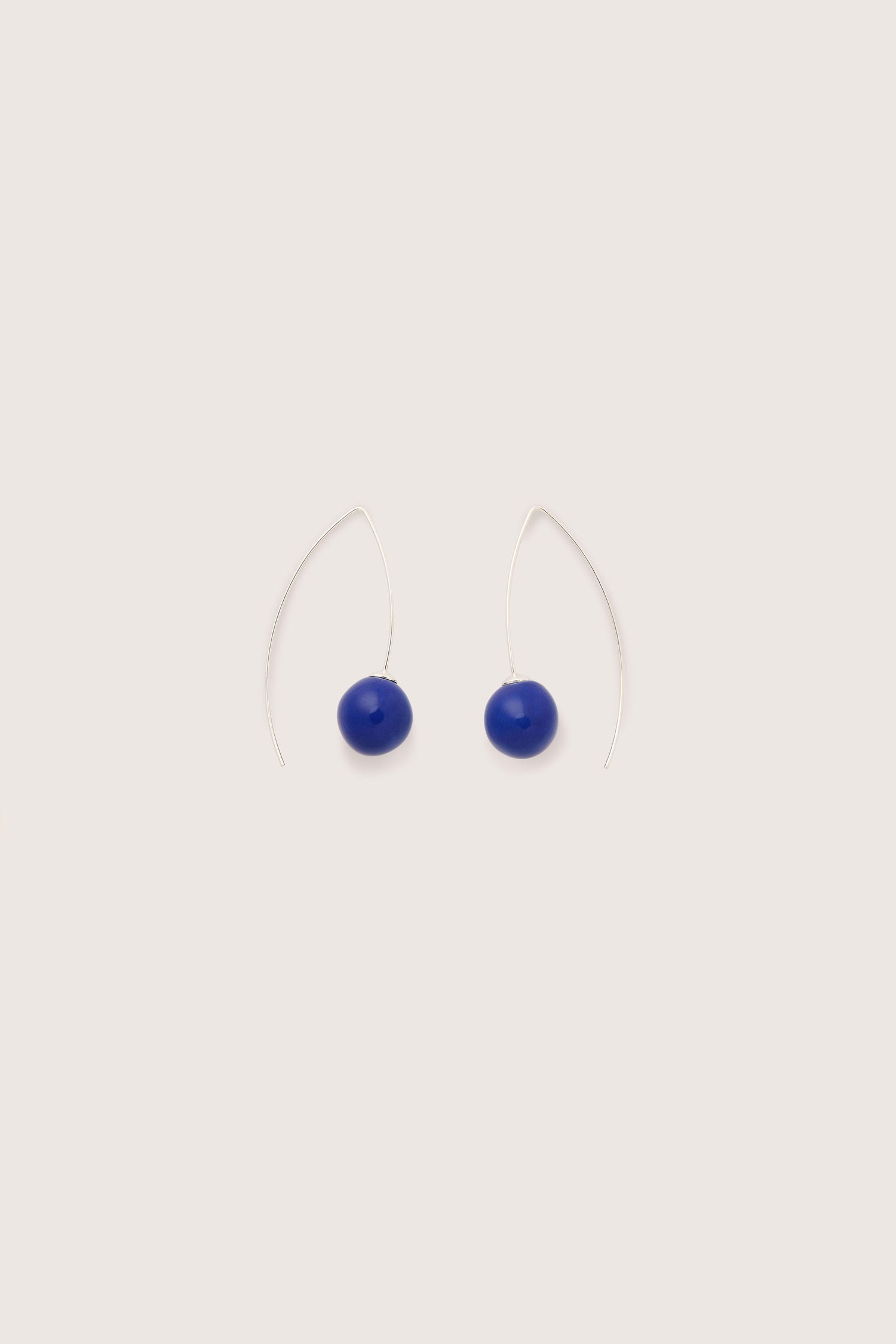 The Handmade Ceramic Bead Earrings are a pair of minimalist silver wire earrings featuring blue oval beads, showcasing artisanal craftsmanship. Fashioned from 925 sterling silver, these handmade ceramic bead earrings bring a touch of elegance to any ensemble.