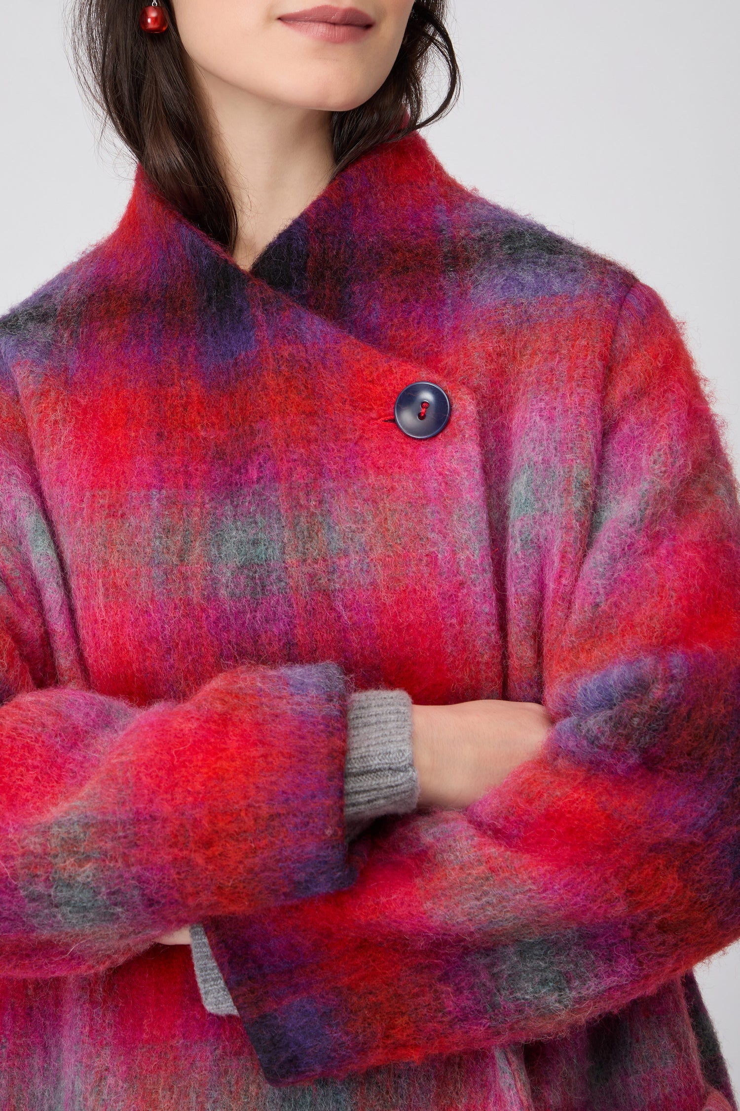 A woman wears the Bright Brushed Check Wool Coat, an oversized piece featuring multicolored checks in red, pink, purple, and black, standing against a plain background.