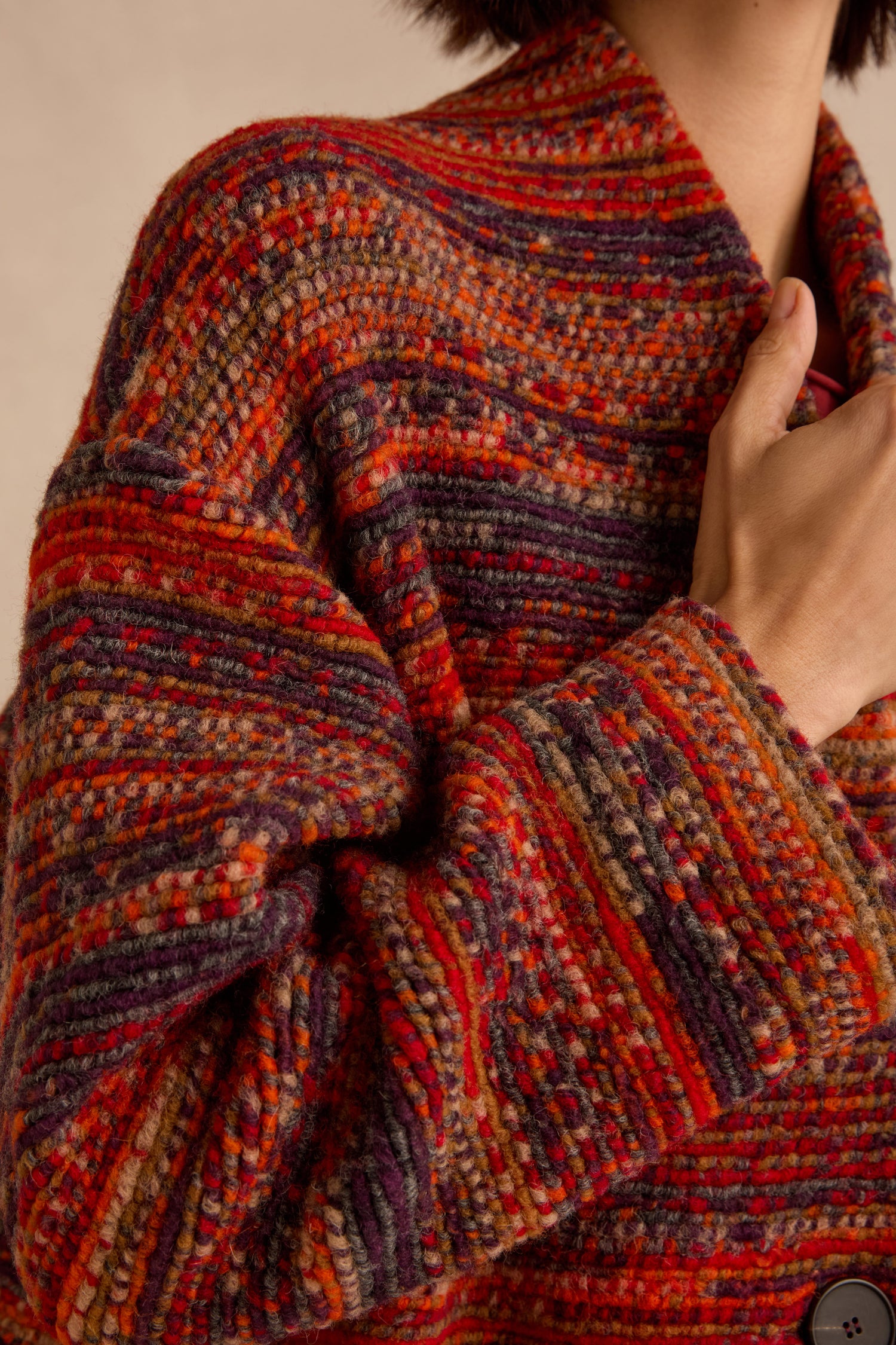 A person is shown from the upper body up, holding the collar of the Artisan Wool Blend Stripe Coat with one hand, revealing a textured knit sweater in red, orange, and purple tones underneath.