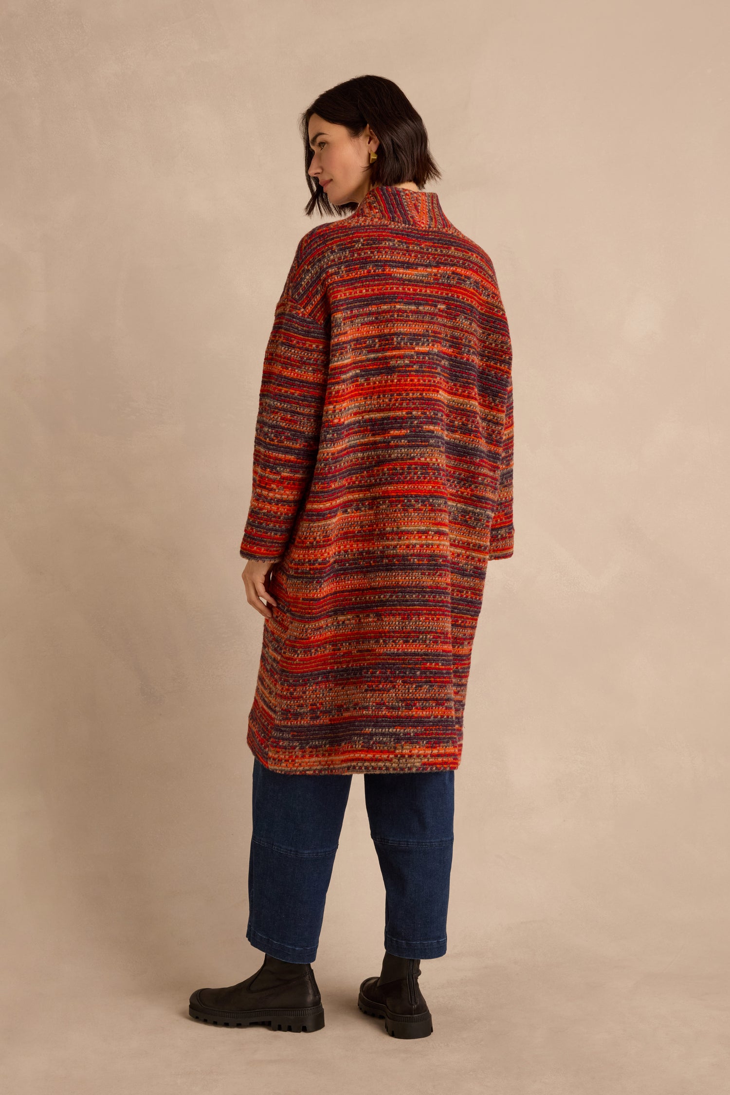 Wearing the Artisan Wool Blend Stripe Coat, a person with short dark hair stands slightly turned away against a beige background, paired with blue jeans and black boots.