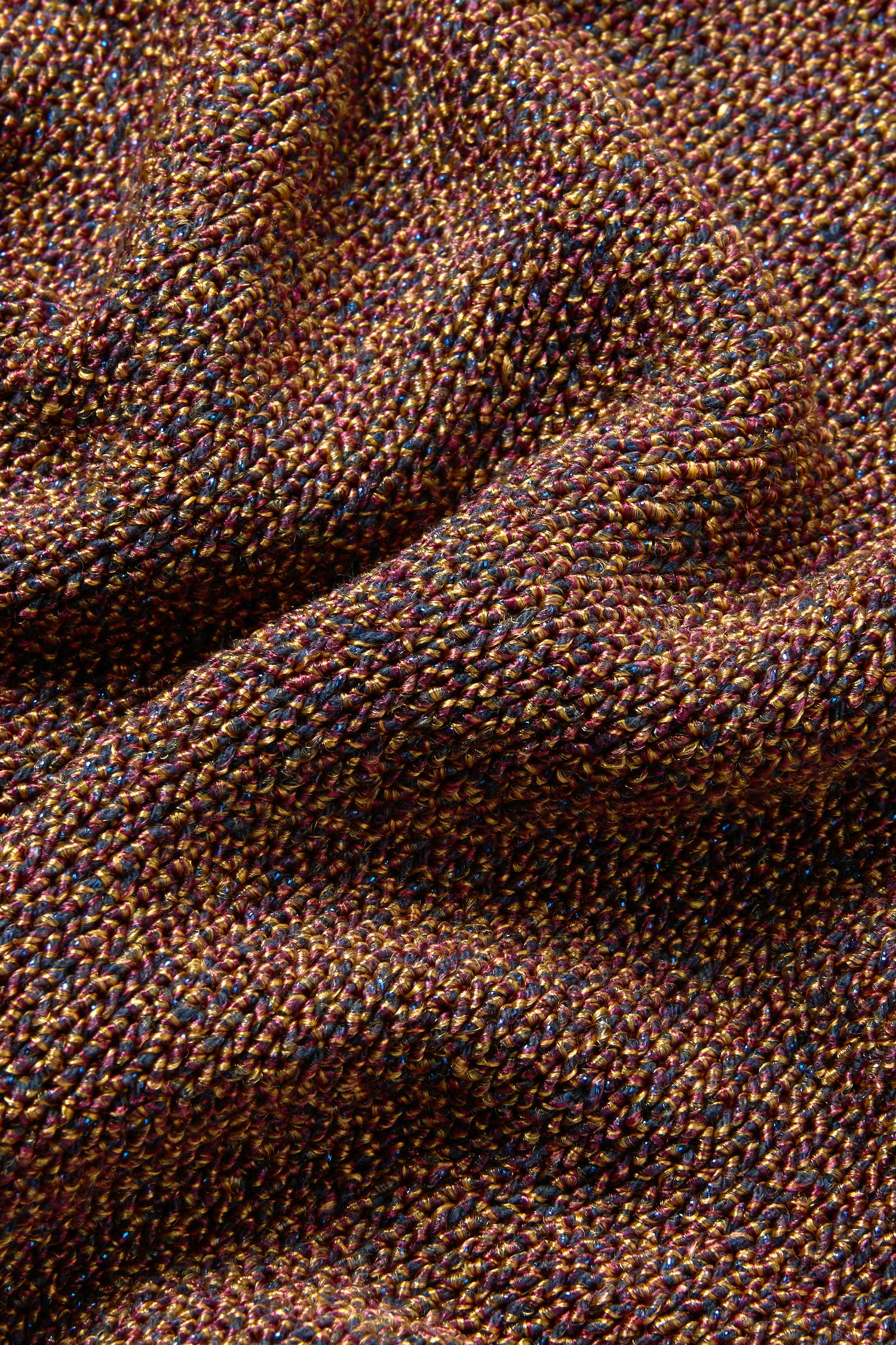 Close-up of textured Italian knit fabric on the Copper Boxy Sparkle Knit Jumper, showing multicolored threads in brown, yellow, and blue with visible folds.