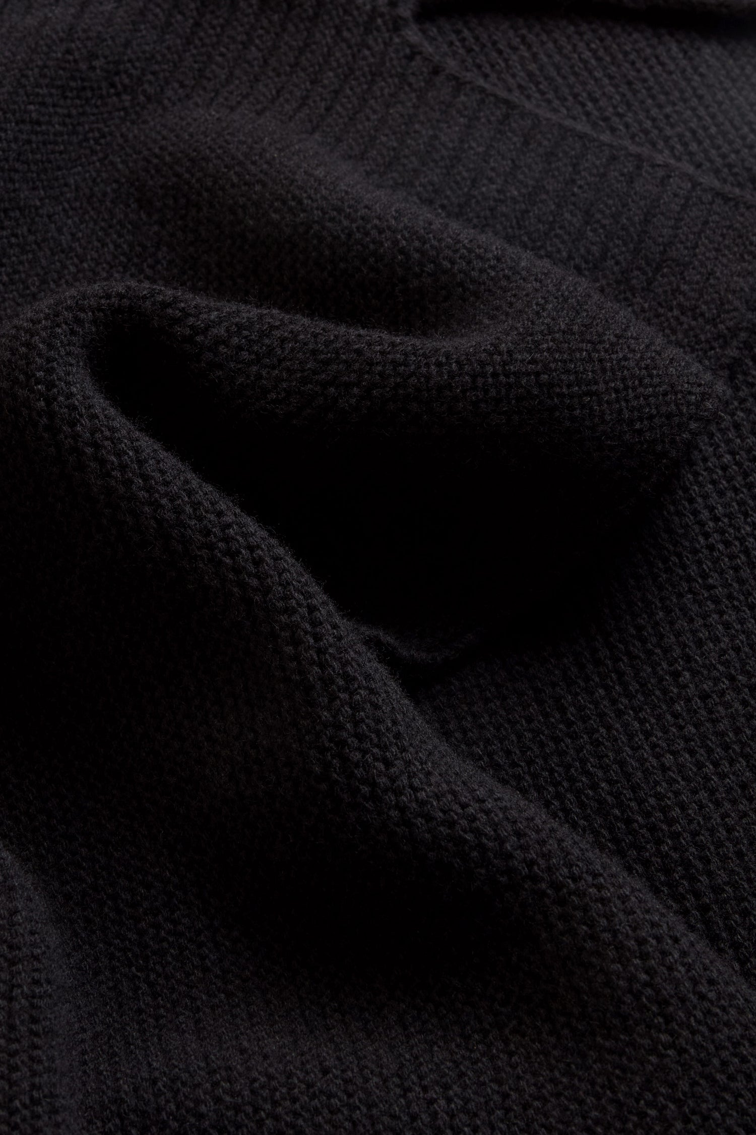 Close-up of the Black Merino Ribbed Turtle Neck Jumper, featuring textured black ribbing and distinctive folds that highlight the classic design of this women’s knit sweater.