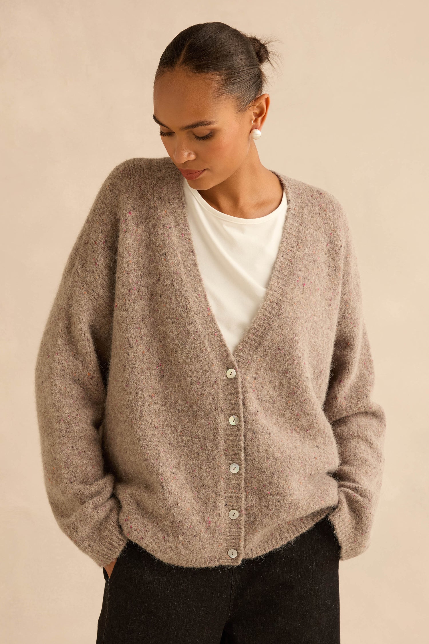 A person wearing a Taupe Alpaca Blend Cropped Cardi over a white t-shirt and black trousers.