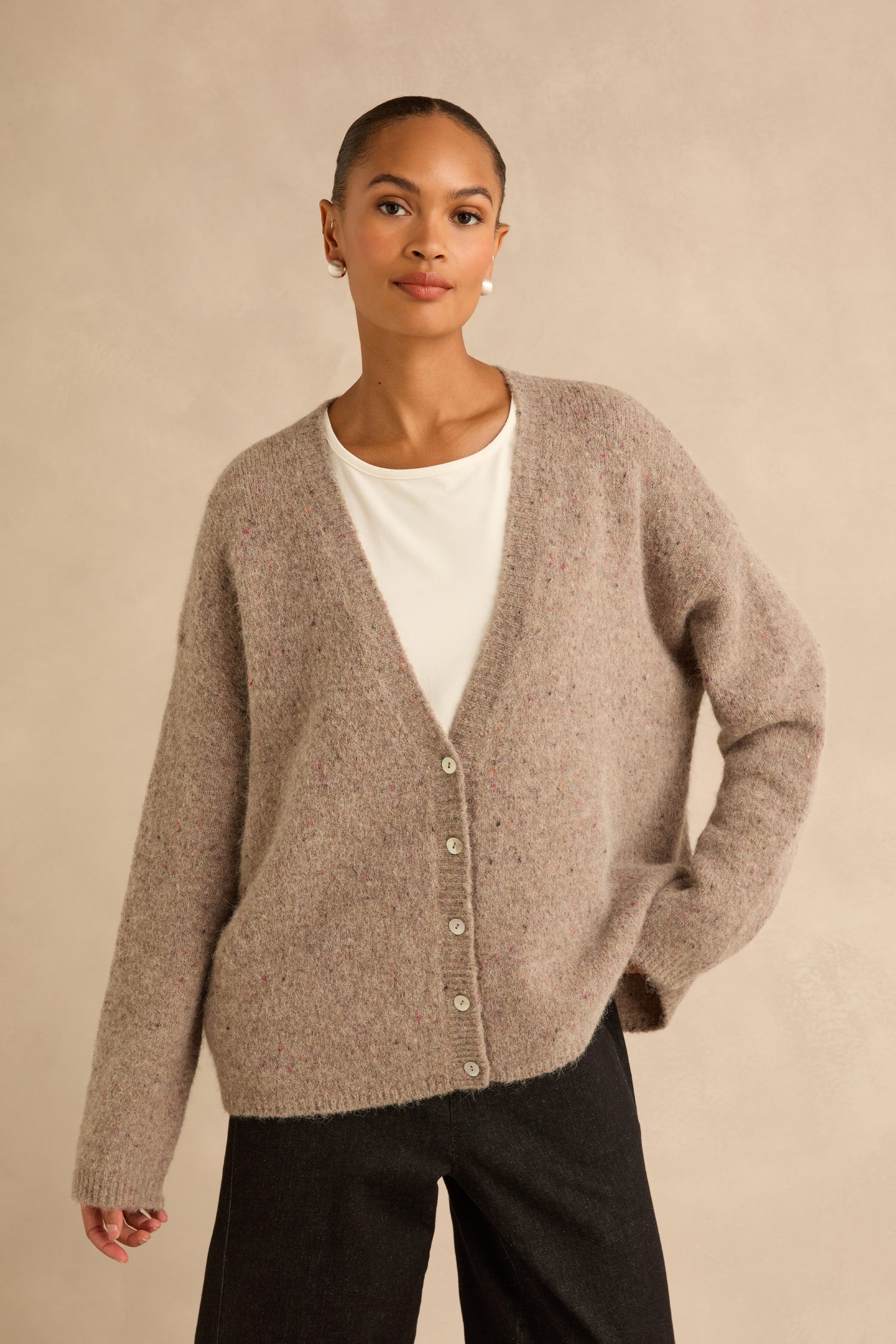 A person wearing a Taupe Alpaca Blend Cropped Cardi in an Italian knit with a V-neck and button-front over a white t-shirt.