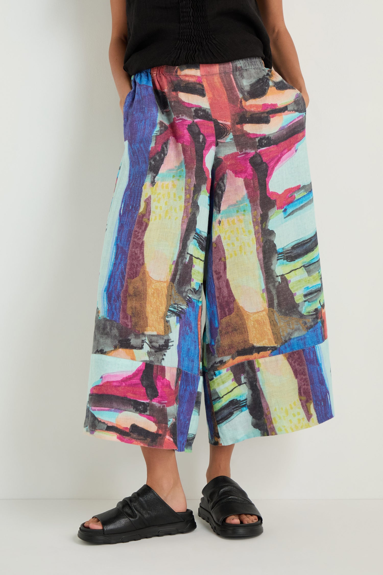 Model wears Abstract Print Wide Leg Trousers with a black top and black open-toe sandals, standing against a plain white background.