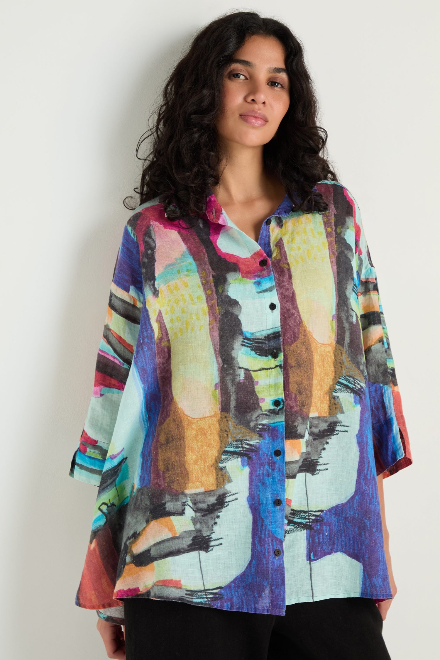 Model wears the Abstract Print Flared Shirt, featuring a loose linen fit and colorful abstract design, posed against a plain light background.