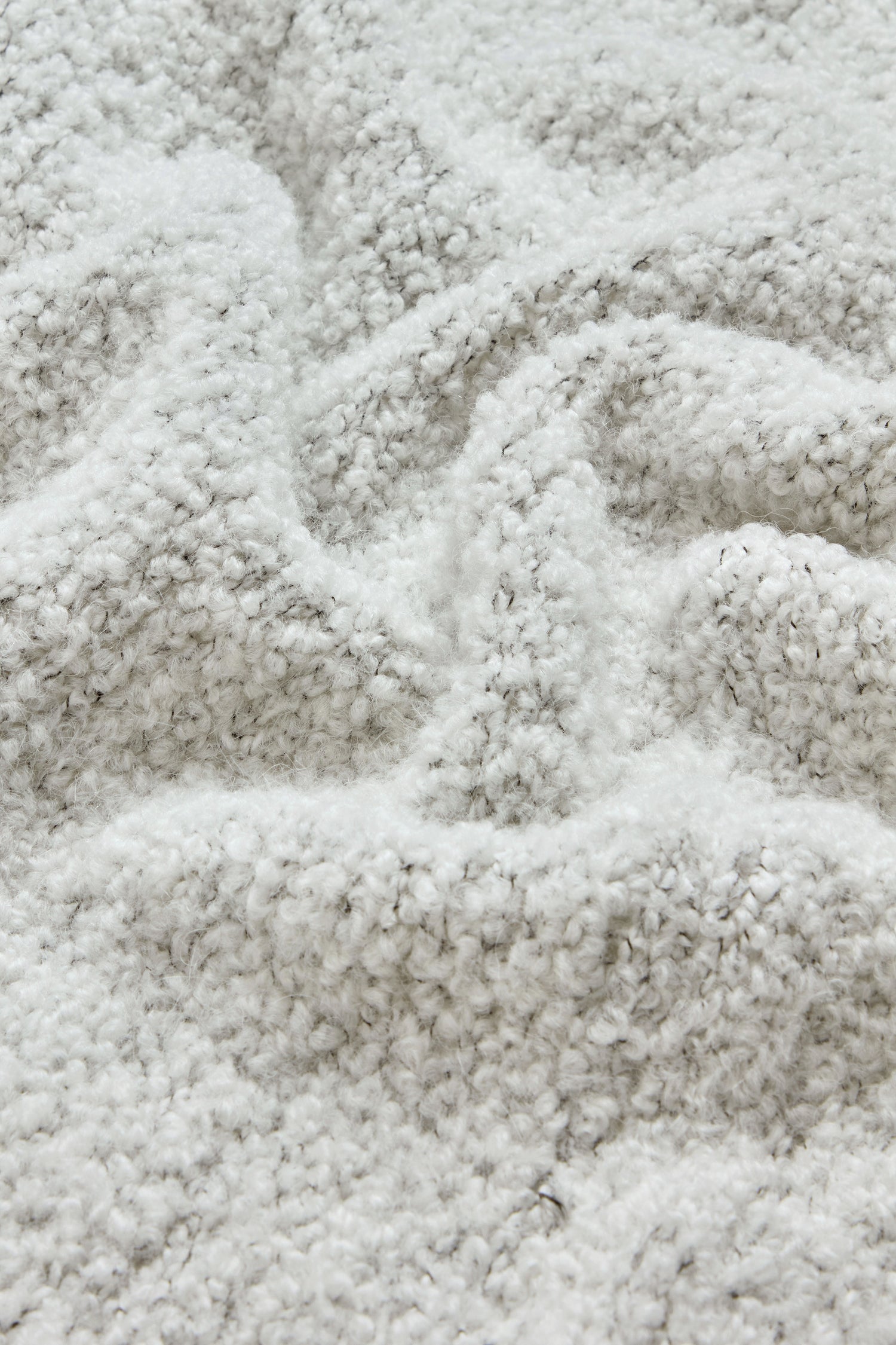 A close-up of the Boucle Collar Cardigan reveals its soft, textured light gray fleece fabric, with visible fibers and gentle folds that evoke the plush comfort of boucle and the cozy warmth of a knit sweater.
