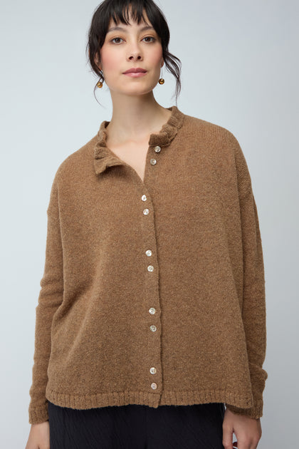 A woman models the Frill Neck Cardi in brown against a plain light backdrop, highlighting this charming layer ideal for knitwear enthusiasts.