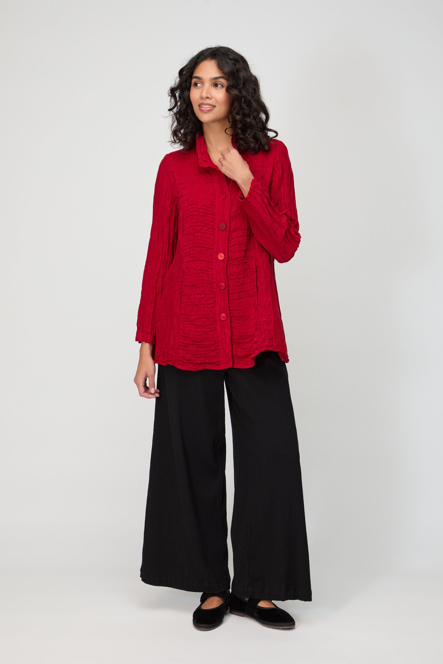 A woman wears the Panel Front Silk Linen Jacket in textured red with long sleeves, paired with wide-leg black pants, posing against a plain light background.