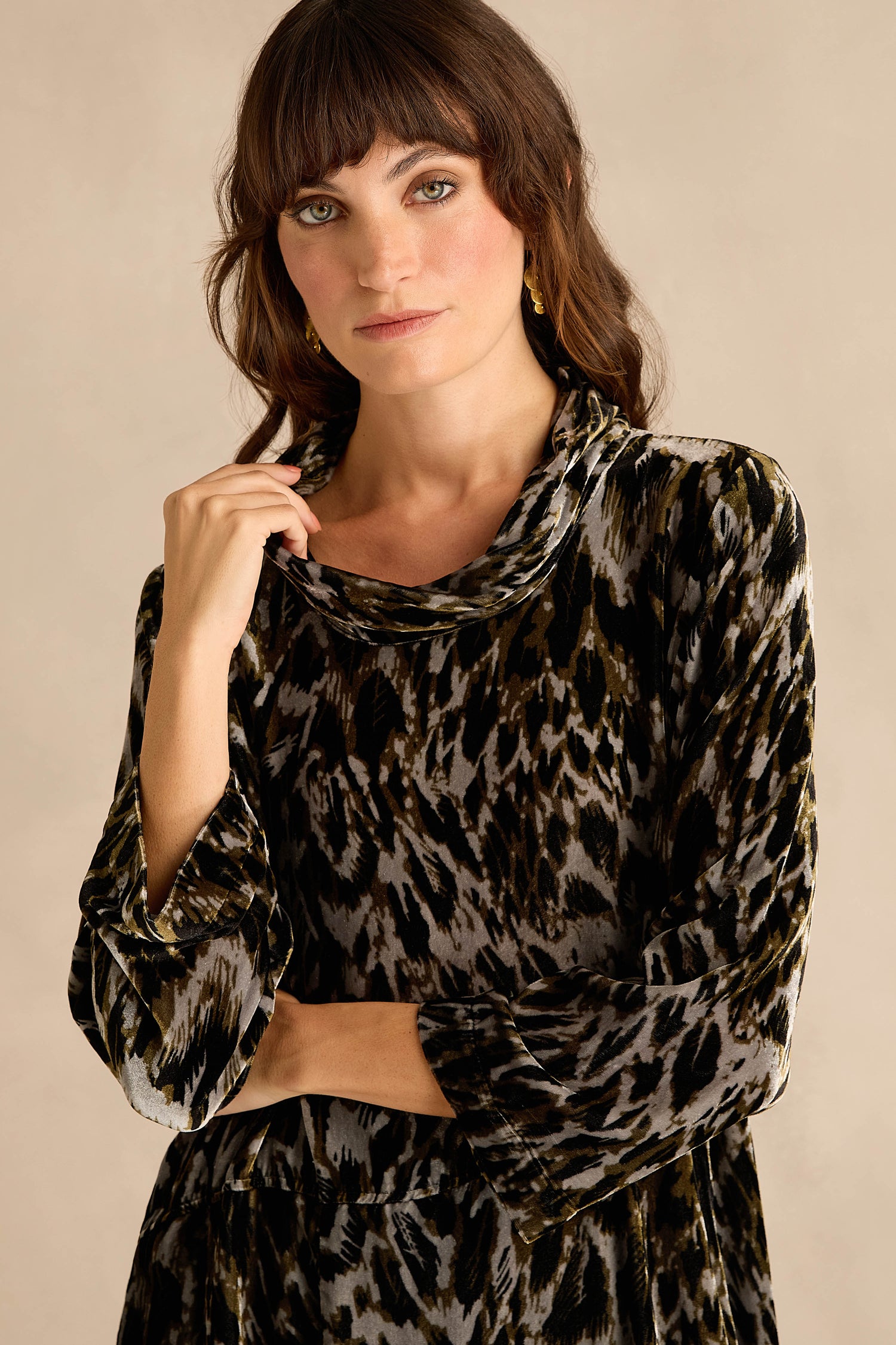A woman with long red hair wears the Animal Print Cowl Neck Velvet Dress, featuring an earth-toned pattern in luxurious silk-blend velvet, shown from the shoulders up against a neutral background.