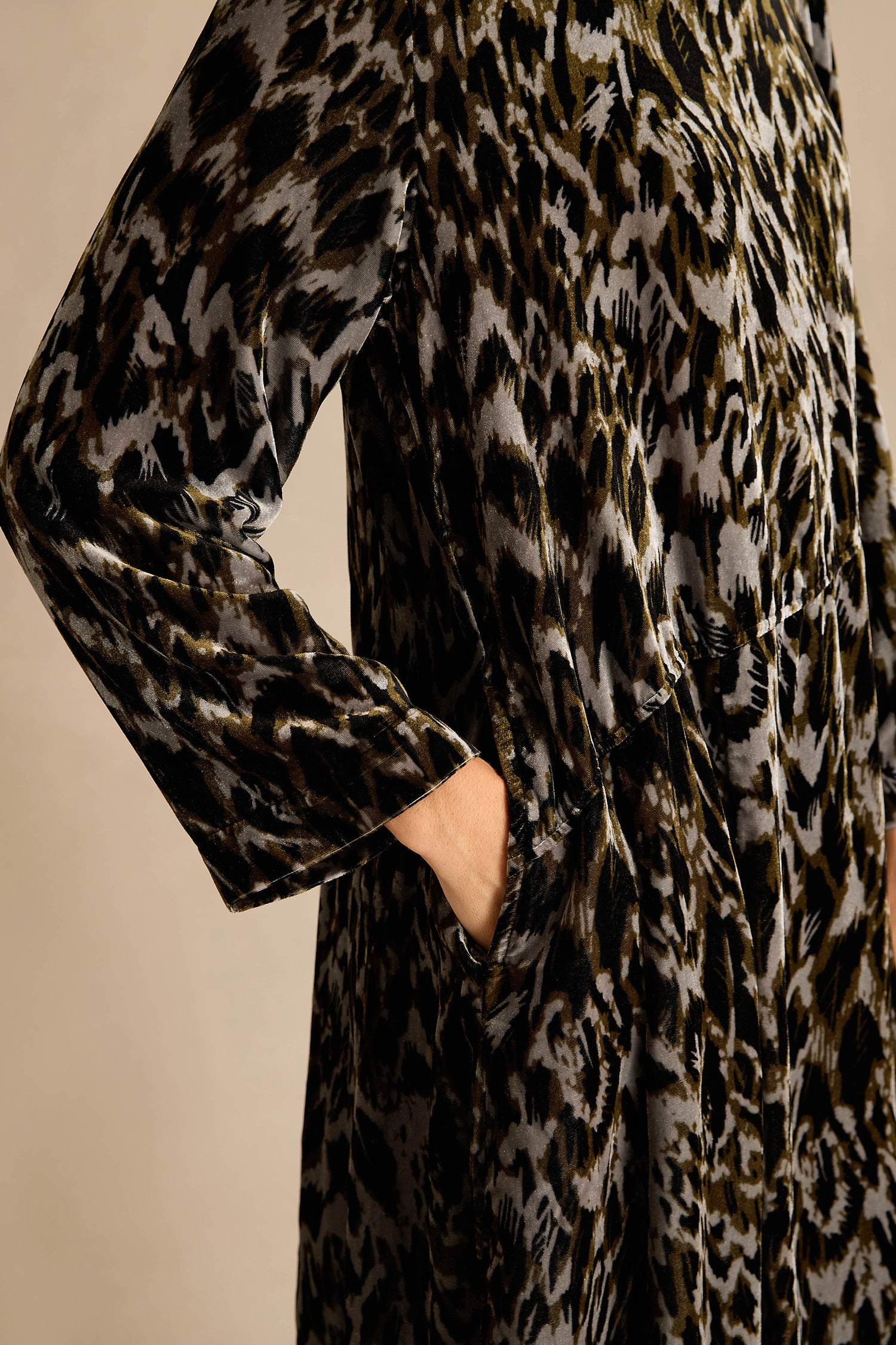 A woman stands against a plain background, wearing the Animal Print Cowl Neck Velvet Dress—a loose, knee-length velvet dress featuring an eye-catching animal print, long sleeves, and a stylish cowl neck—paired with black knee-high boots.