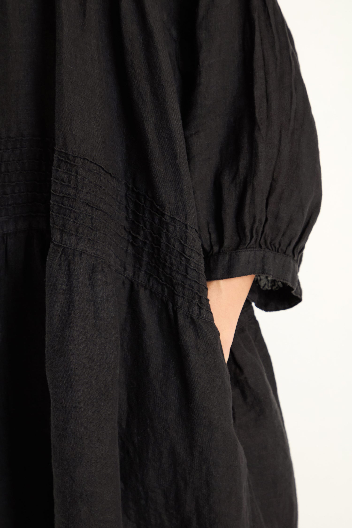 Close-up of a person wearing the Easy Fit V-Neck Black Linen Dress, featuring a gathered waist and side pocket, against a plain background.