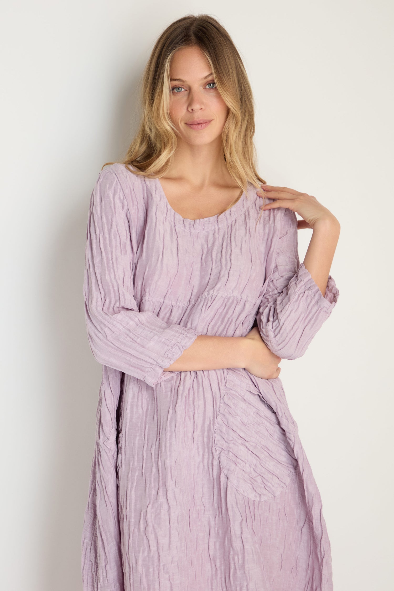 A woman with long blonde hair wears the Silk Linen Lilac Patch Pocket Dress with long sleeves, standing against a plain light background.