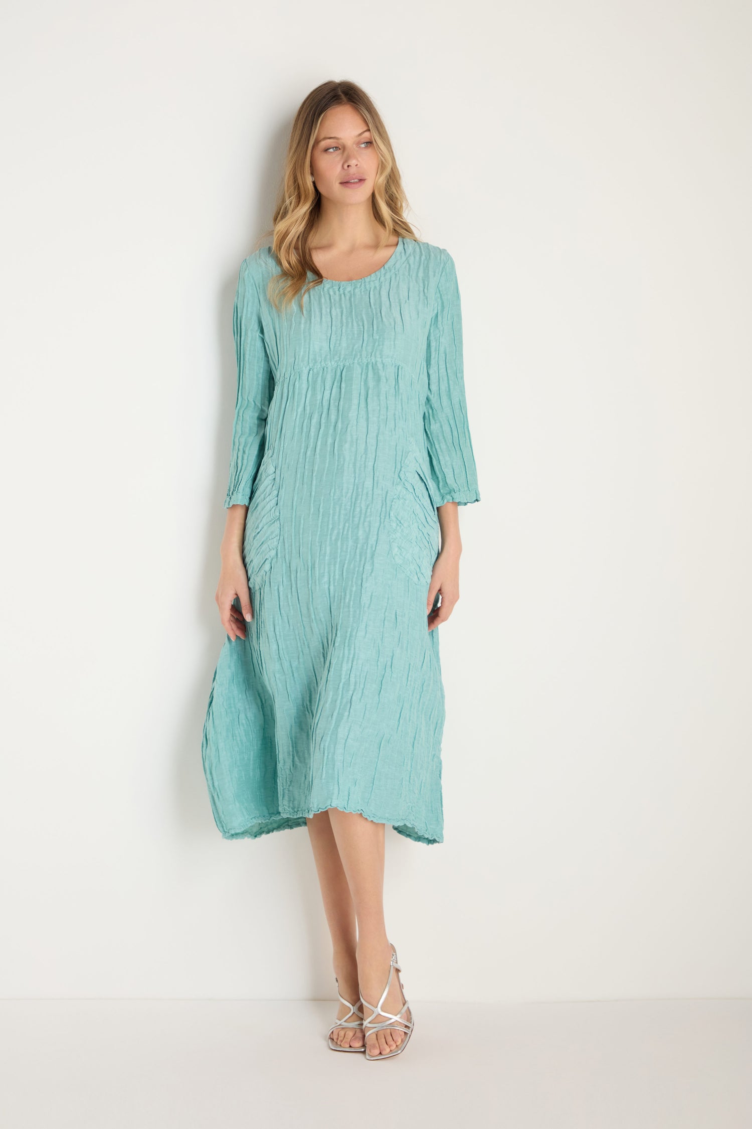 Woman wearing a Silk Linen Mint Patch Pocket Dress with three-quarter sleeves and white strappy sandals, standing against a plain white background.