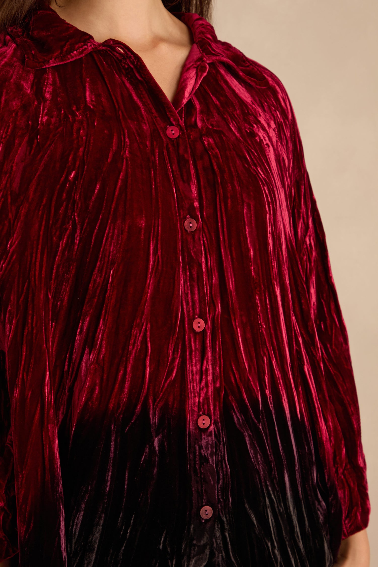 Person wearing a Ruby Silk Velvet Ombre Shirt—a loose, collared, button-up in red velvet with a shiny texture and soft drape. Upper body only is visible.