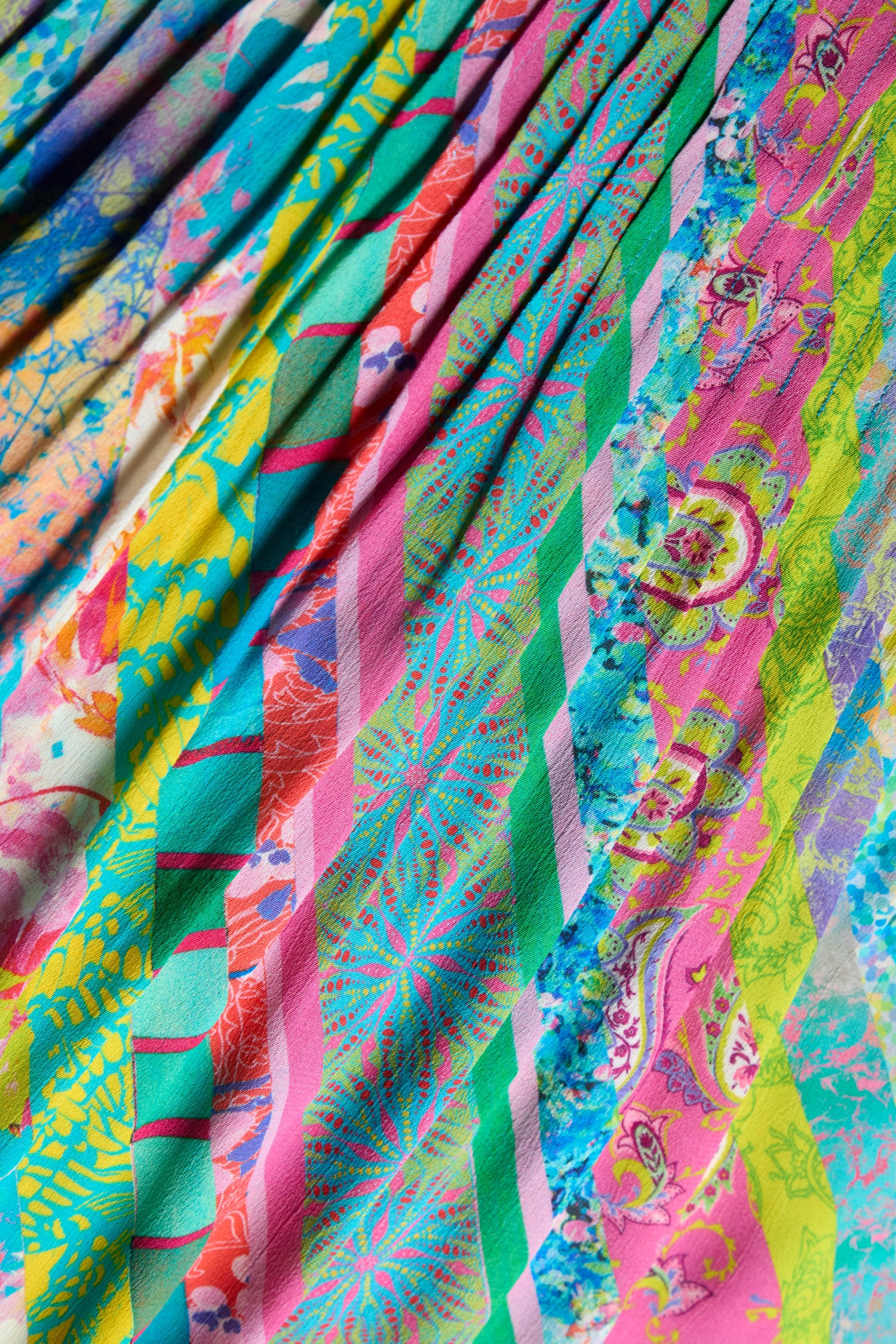 Close-up of the Patchwork Stripe Pleated Dress, showcasing pleats with diagonal multicolor stripes and floral patterns—ideal for a bold fit and flare look.