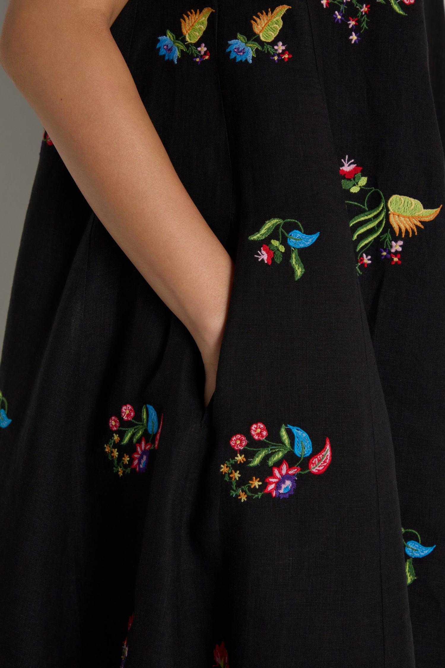 Close-up of a hand in the pocket of the Vintage Floral Embroidered Bubble Dress, featuring black fabric with colorful embroidery.