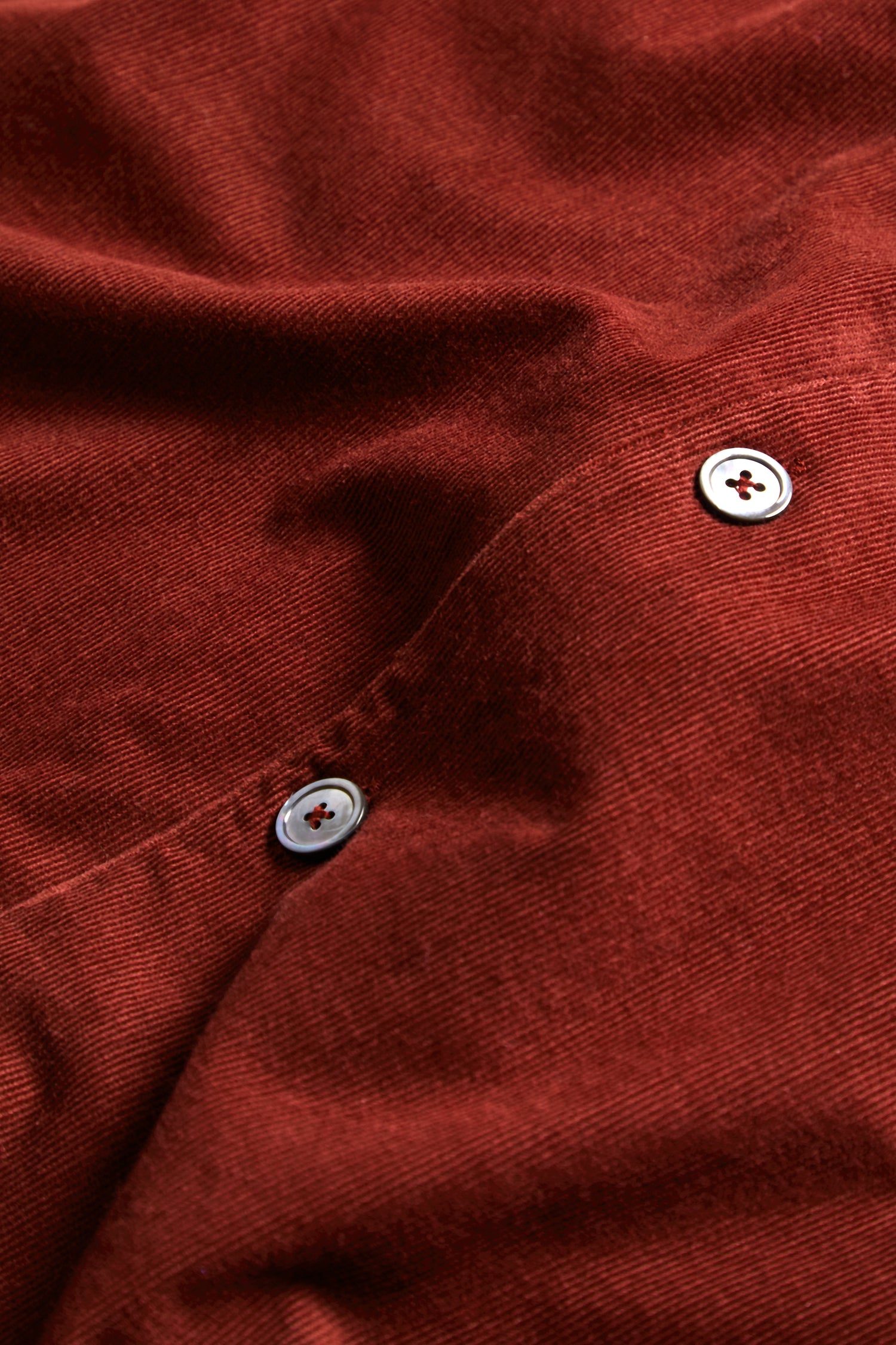 Close-up of the Conker Pinwale Cord Shirt Dress in red cotton cord, featuring two white buttons and visible seam detailing.