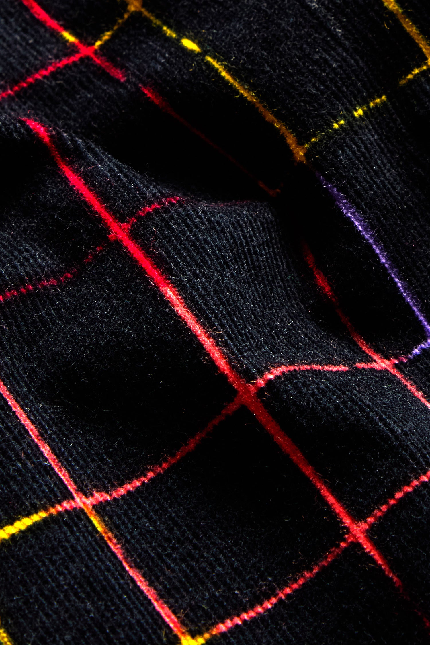 Close-up of the Stitched Check Cord Skirt showcasing a black fabric with vibrant red, yellow, and purple lines in a check pattern.
