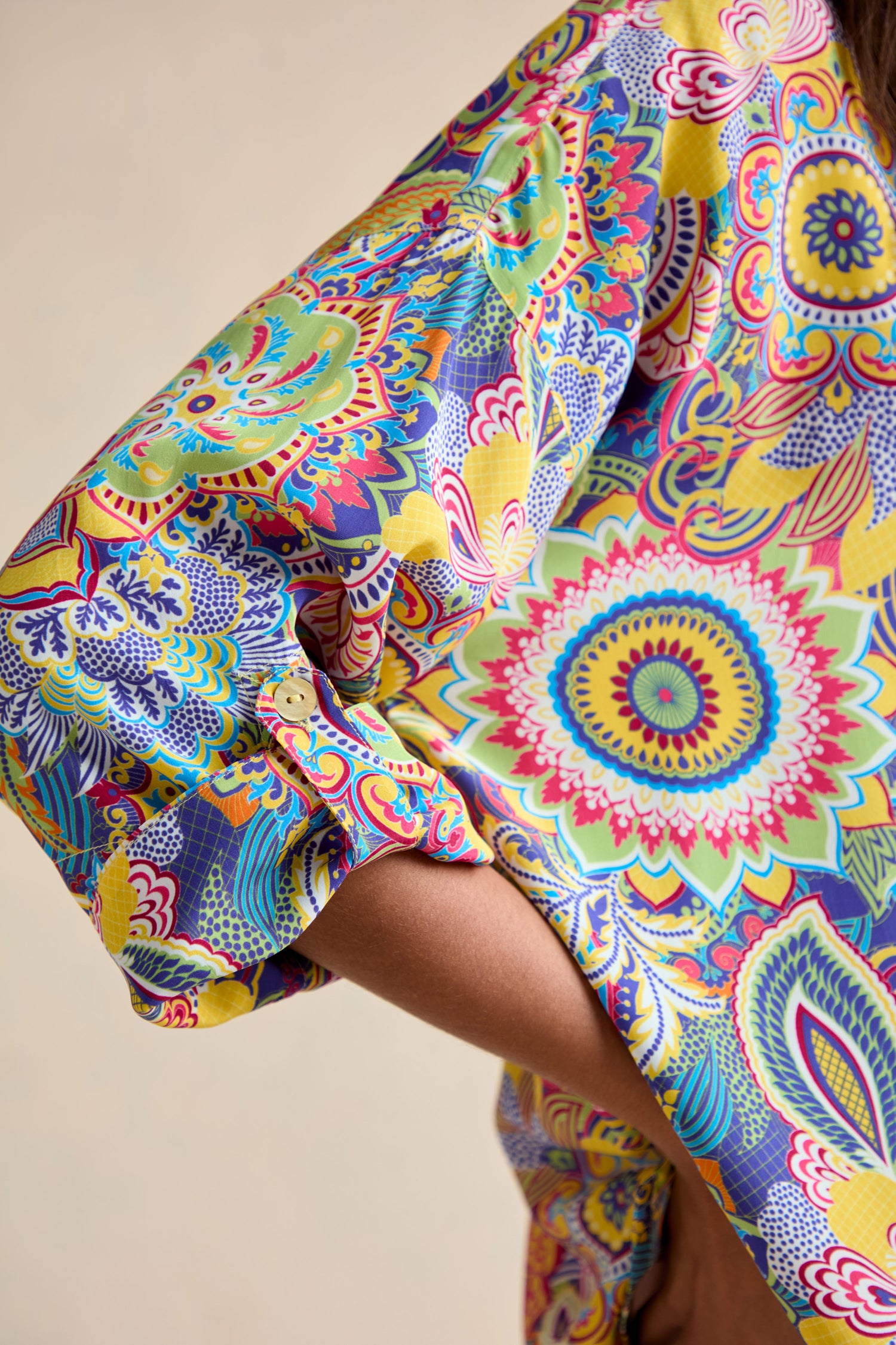 Close-up of a bent arm wearing the Summer Sarasa Relaxed Shirt, featuring a vibrant multicolored floral and geometric Sarasa print in a relaxed, boxy silhouette.