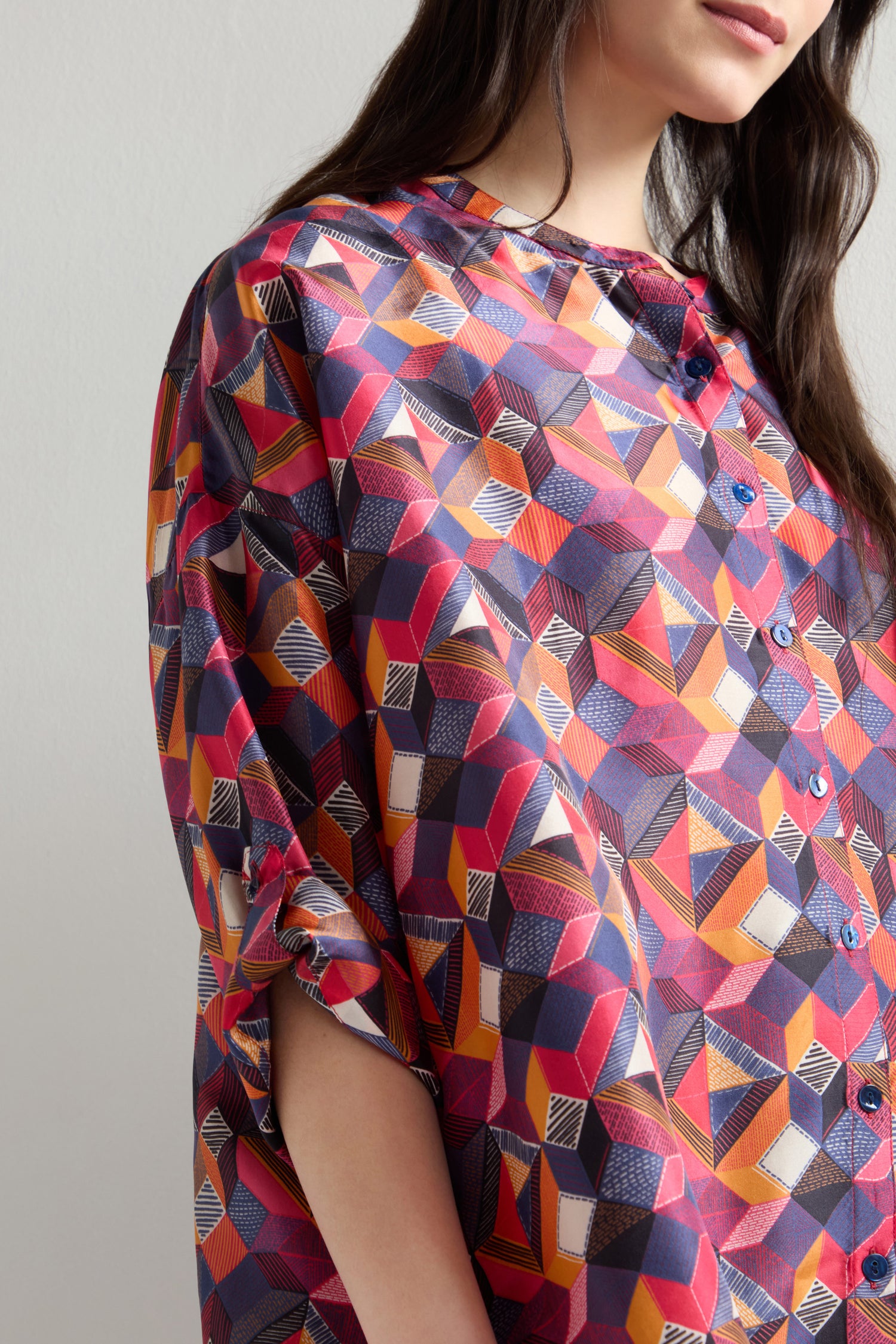 A person wearing a Small Stitched Squares Silk Shirt featuring an oversized fit and a vibrant geometric square print in red, pink, and blue.